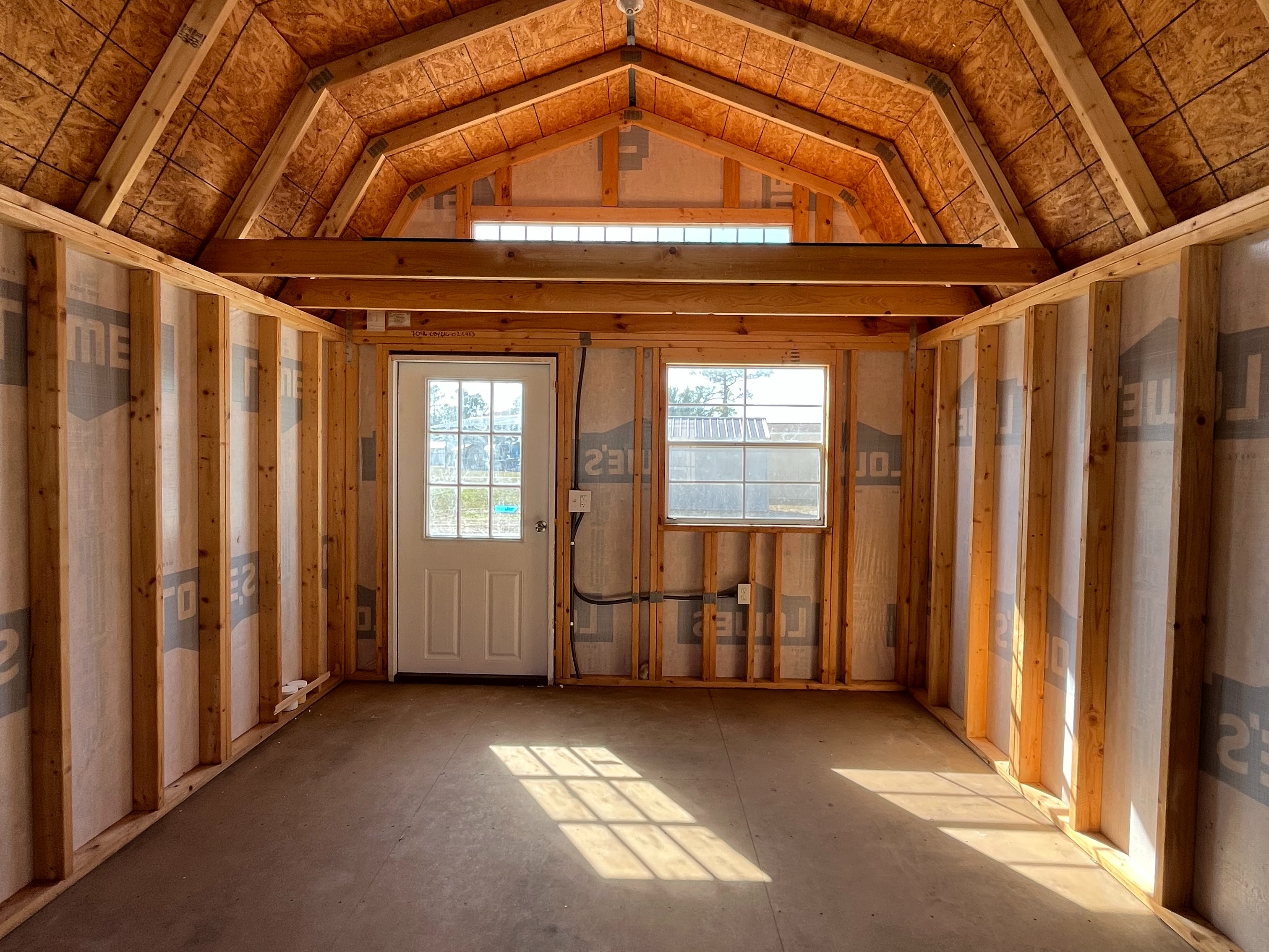 Interior front wall view of a 12x16 lofted barn showing the walk-in door,  windows, loft, any many more features