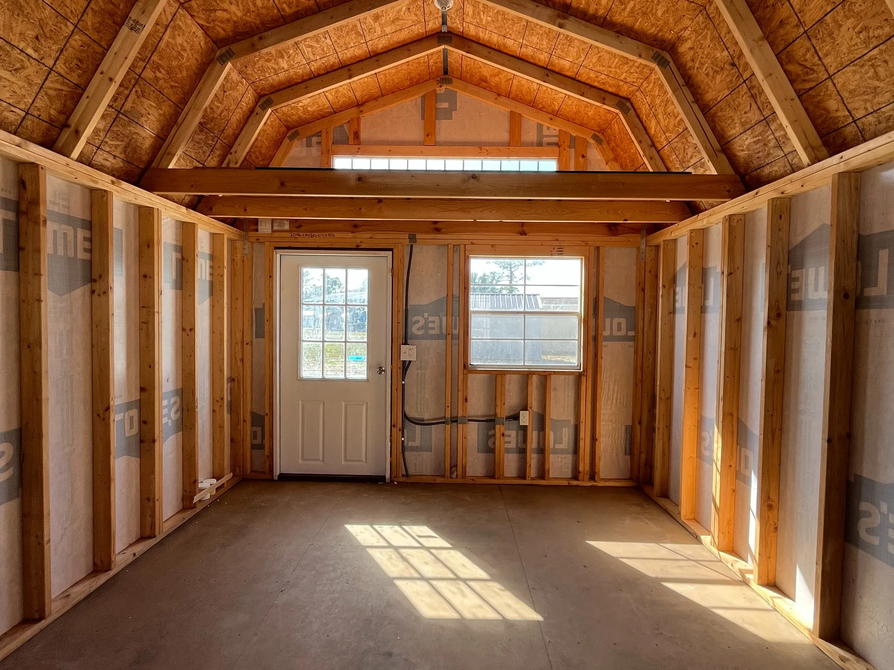 Interior front wall view of a 12x16 lofted barn showing the walk-in door, windows, loft, any many more features