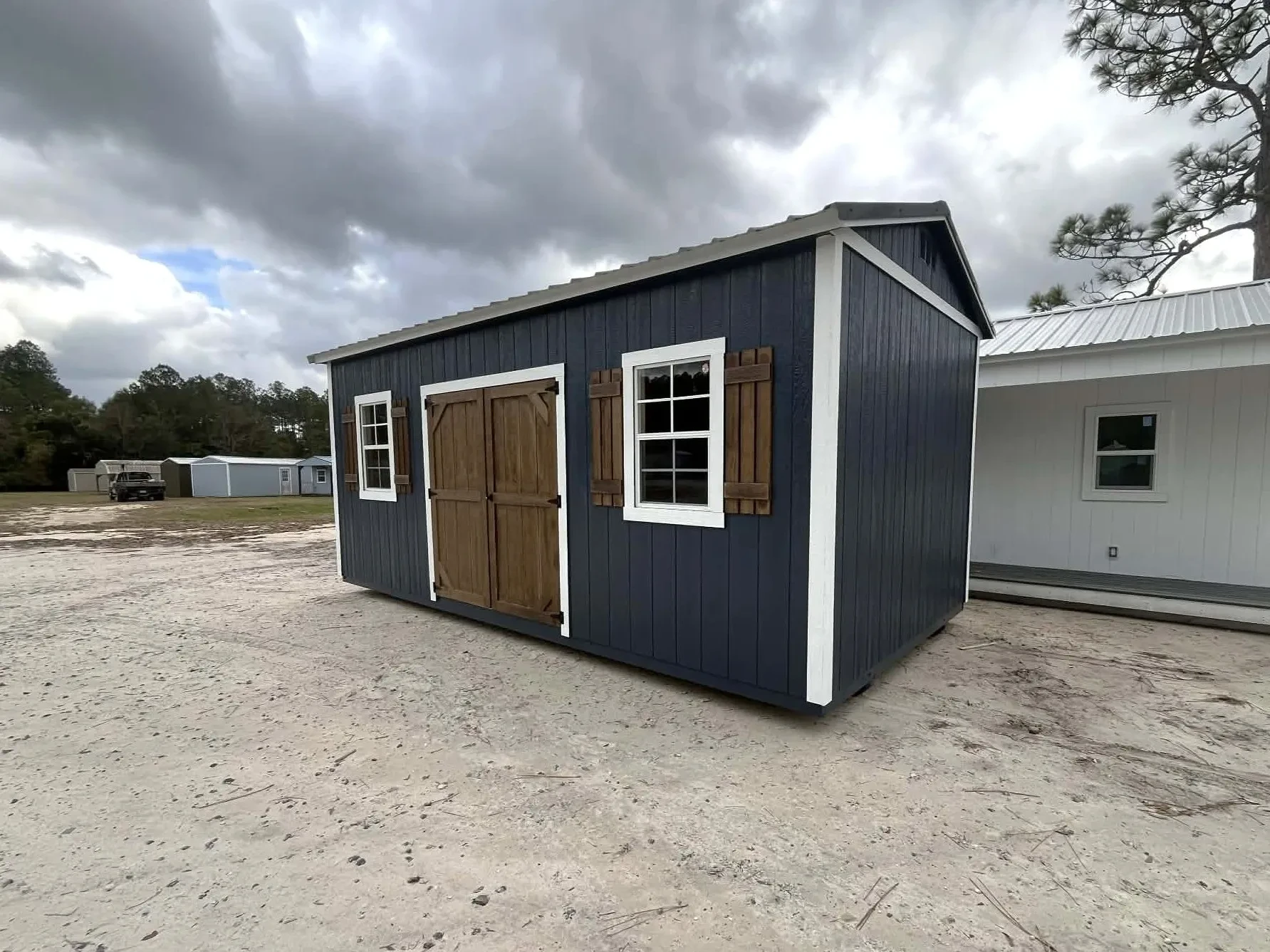 Exterior right angle of a dark blue 10x20 side garden shed showing double wood doors, windows and shutters