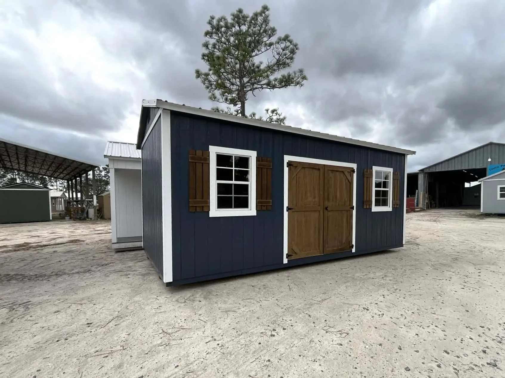 Exterior left angle of a dark blue 10x20 side garden shed showing double wood doors, windows and shutters