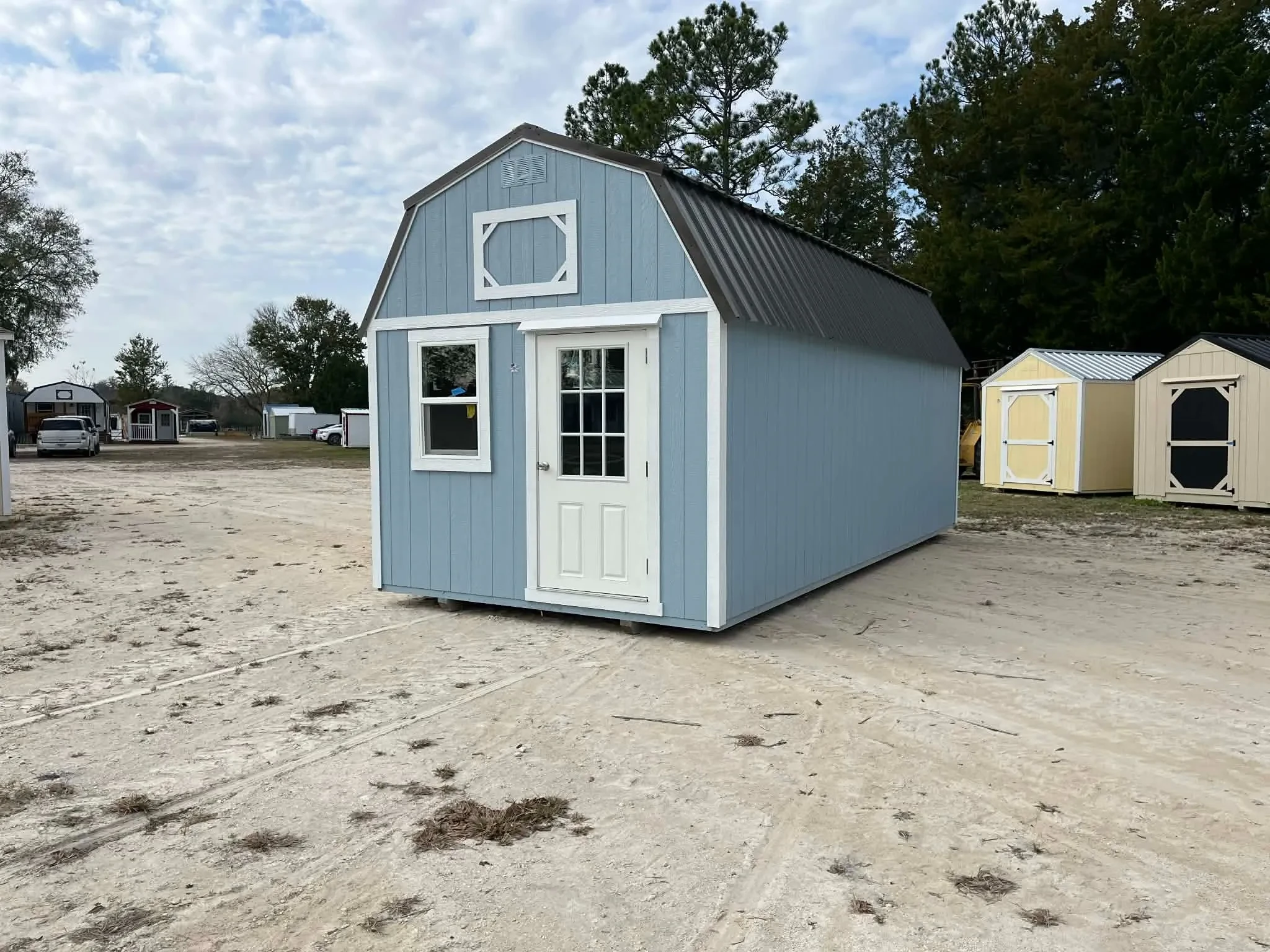 Exterior front and right side view of a light blue 10x24 lofted barn with a walk-in door and window
