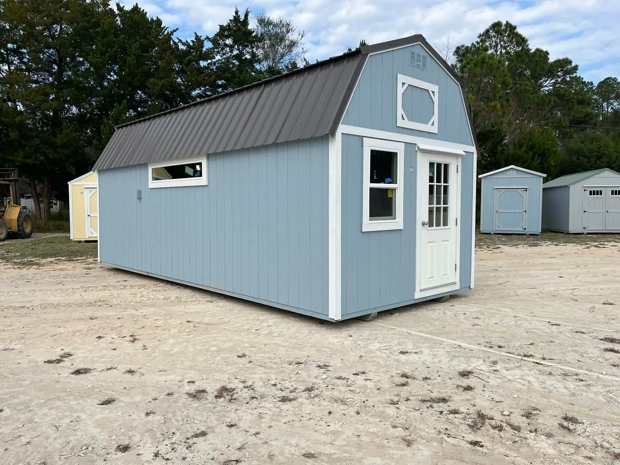 Exterior front and left side view of a light blue 10x24 lofted barn with a walk-in door, window and transom