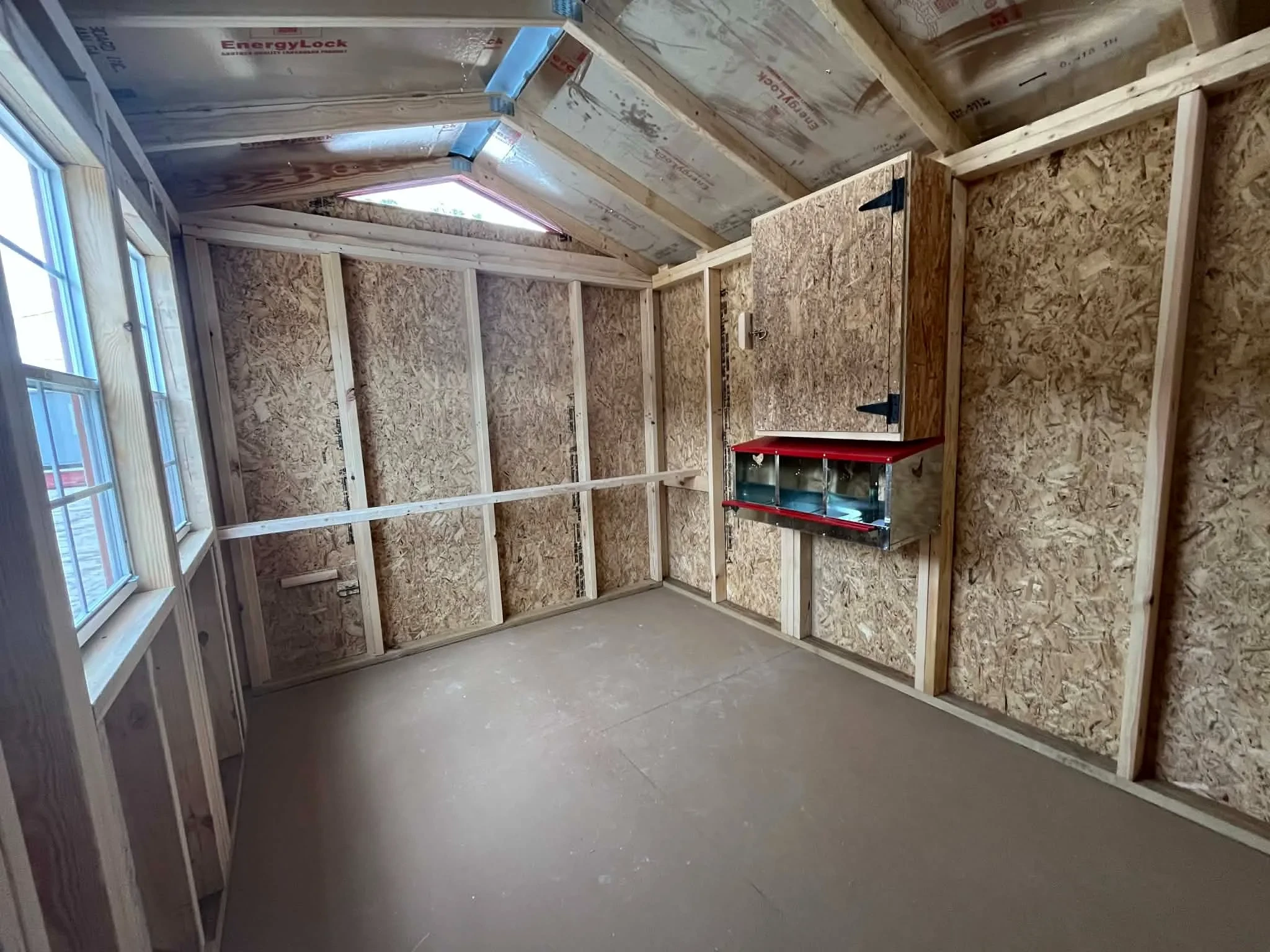 Interior of an 8x12 chicken coop viewing from the door showing the layer boxes and roosting bar