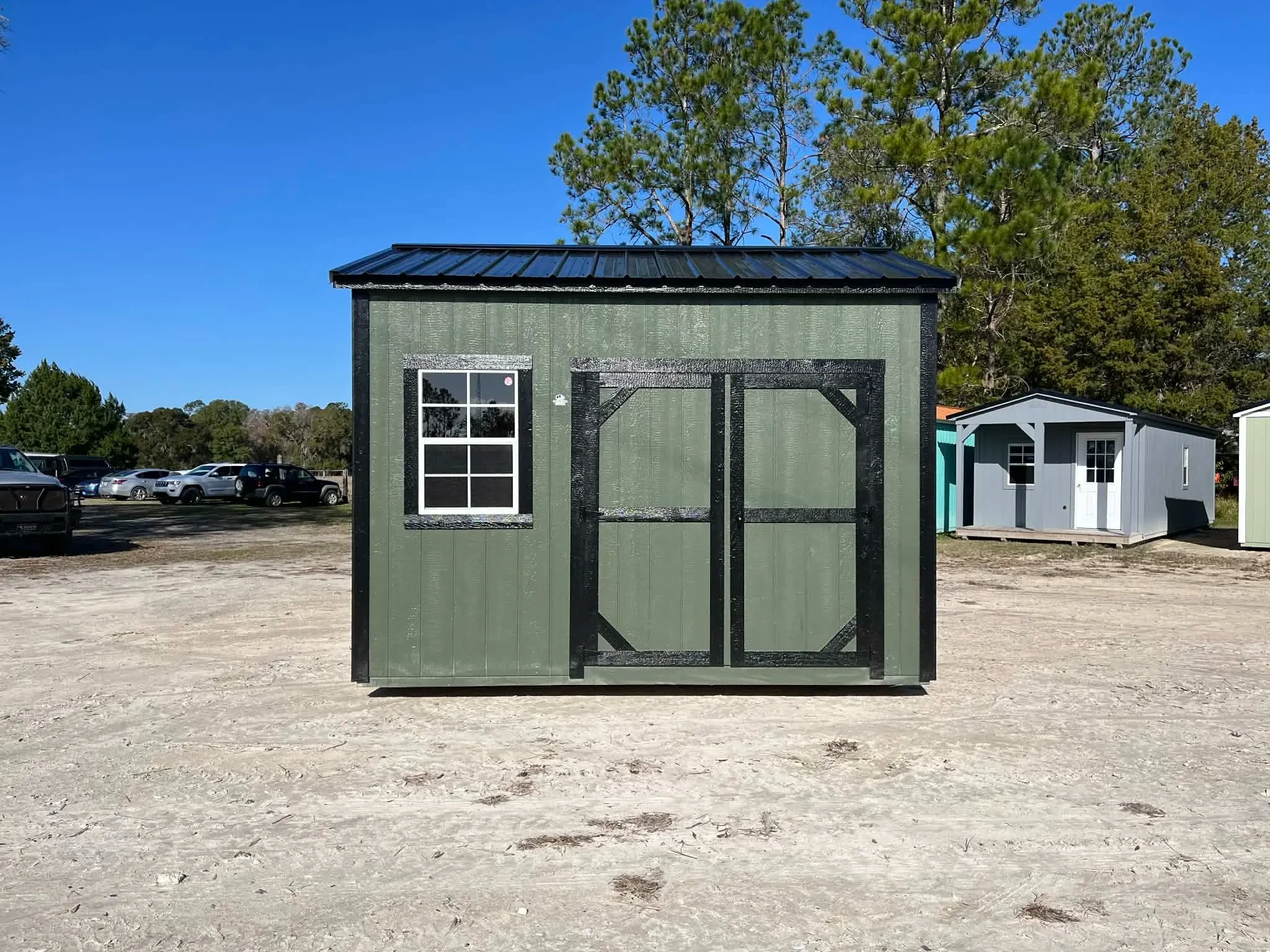Exterior view of a green 10x12 side garden shed showing wood door and window