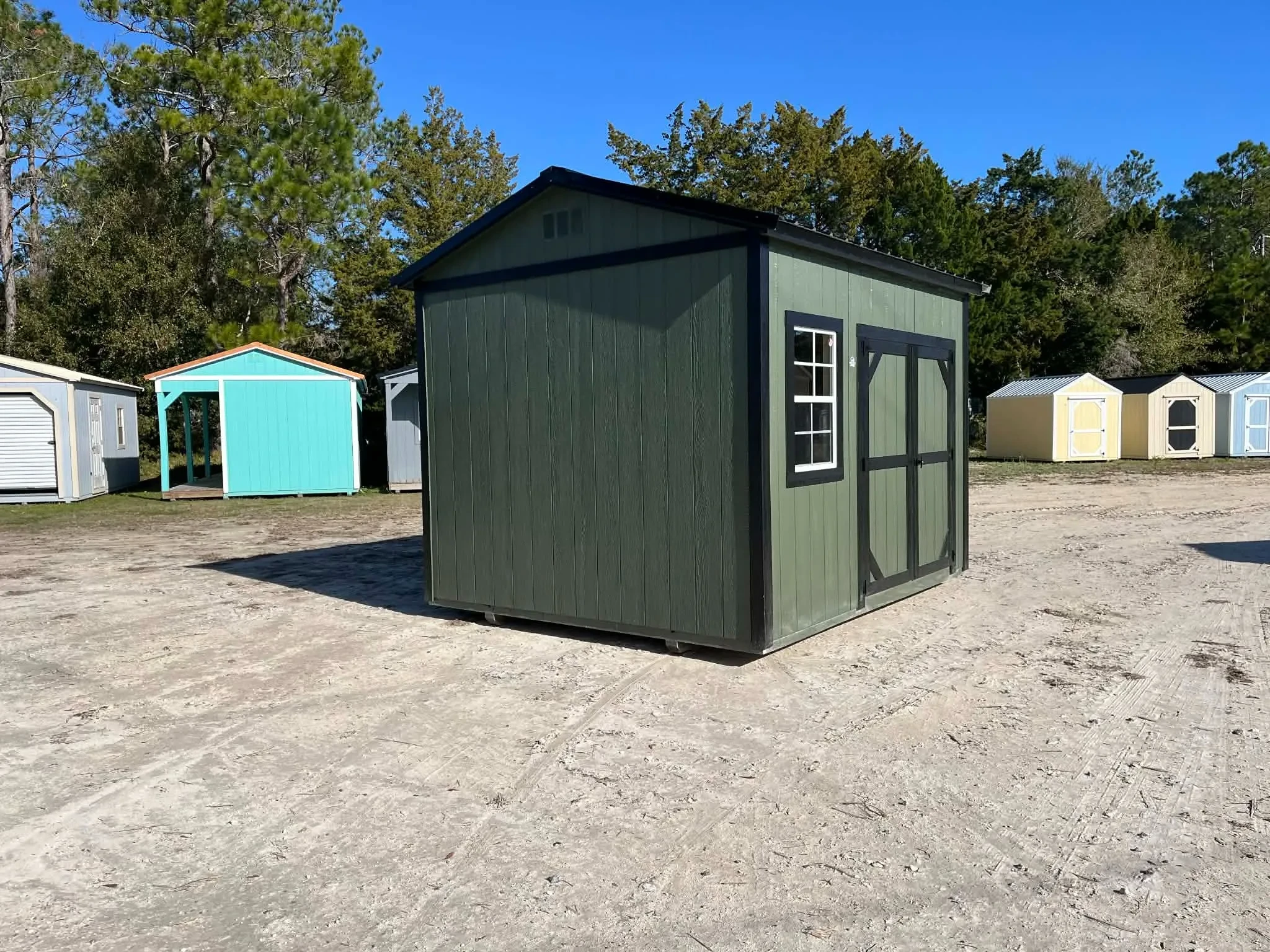 Exterior view of a green 10x12 side garden shed showing wood door and window