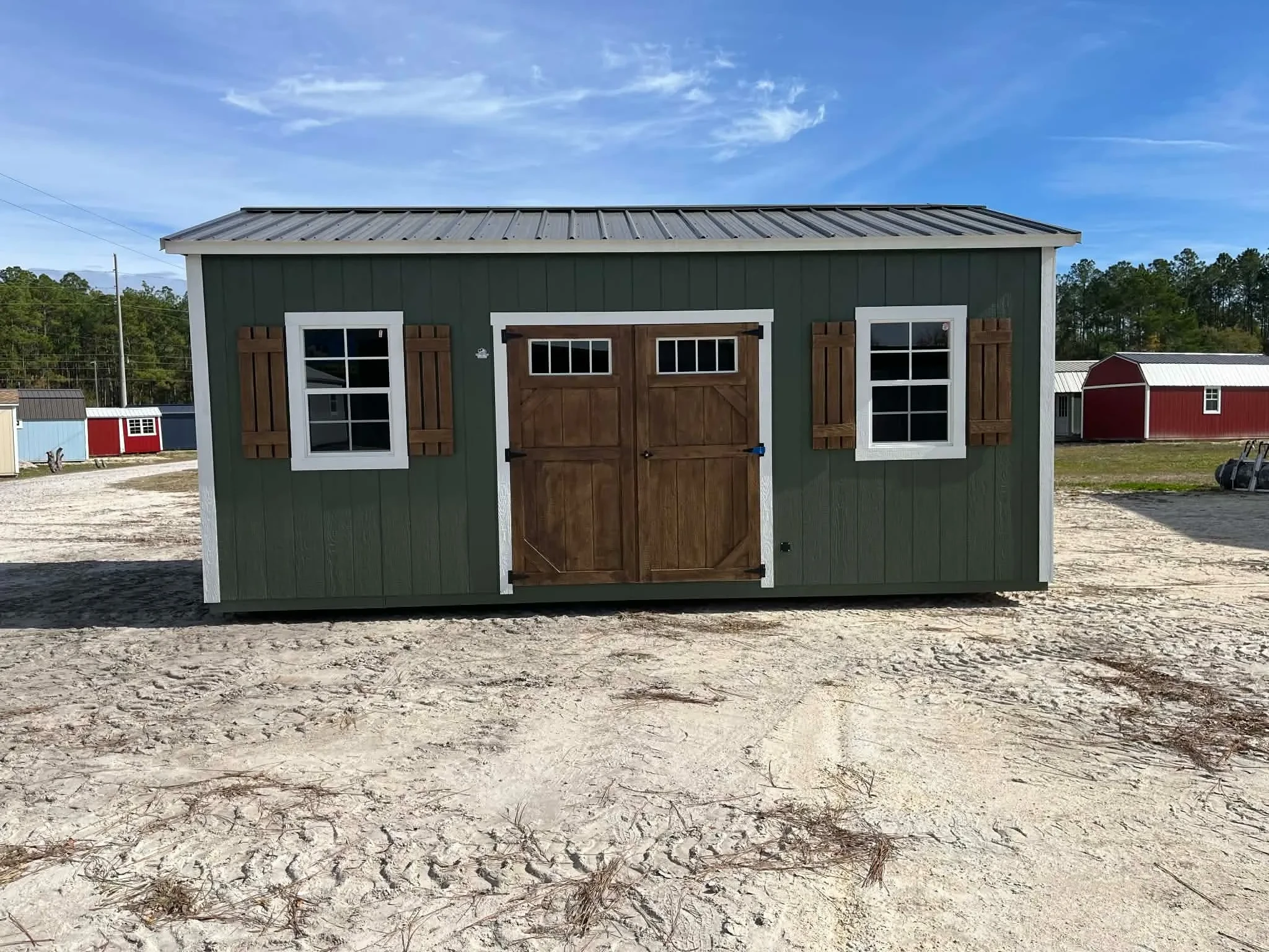 Exterior of a green 10x20 side garden shed showing doors and window