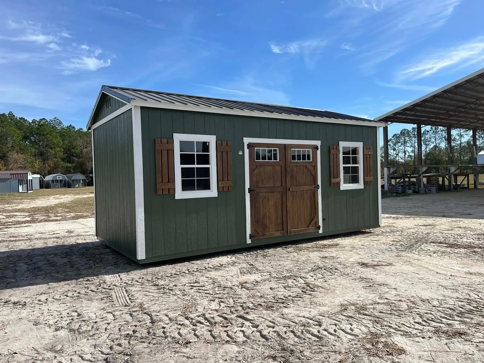 Exterior of a green 10x20 side garden shed showing doors and window