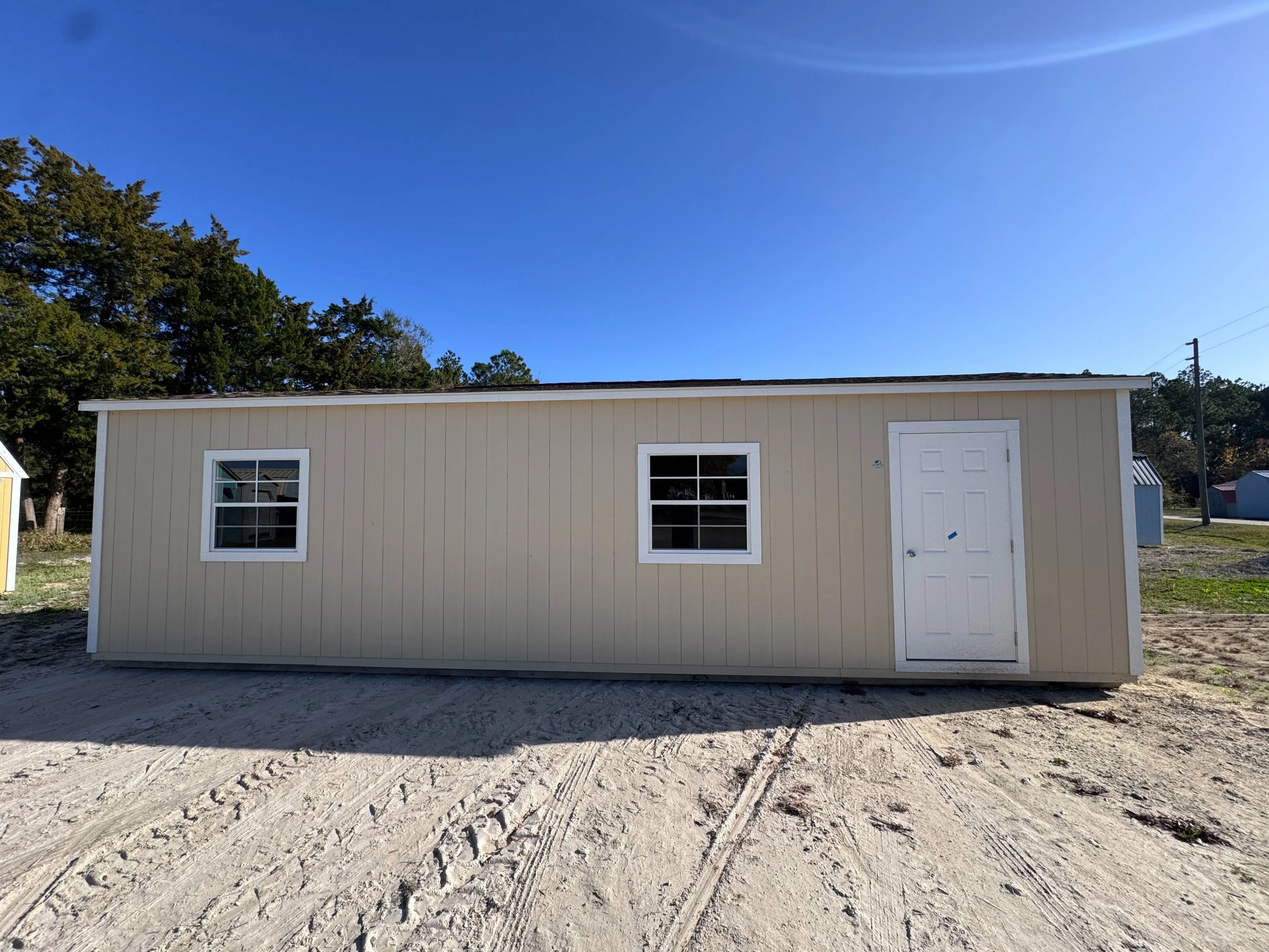 Side view of almond 12x32 workshop with white trim, entry door and windows