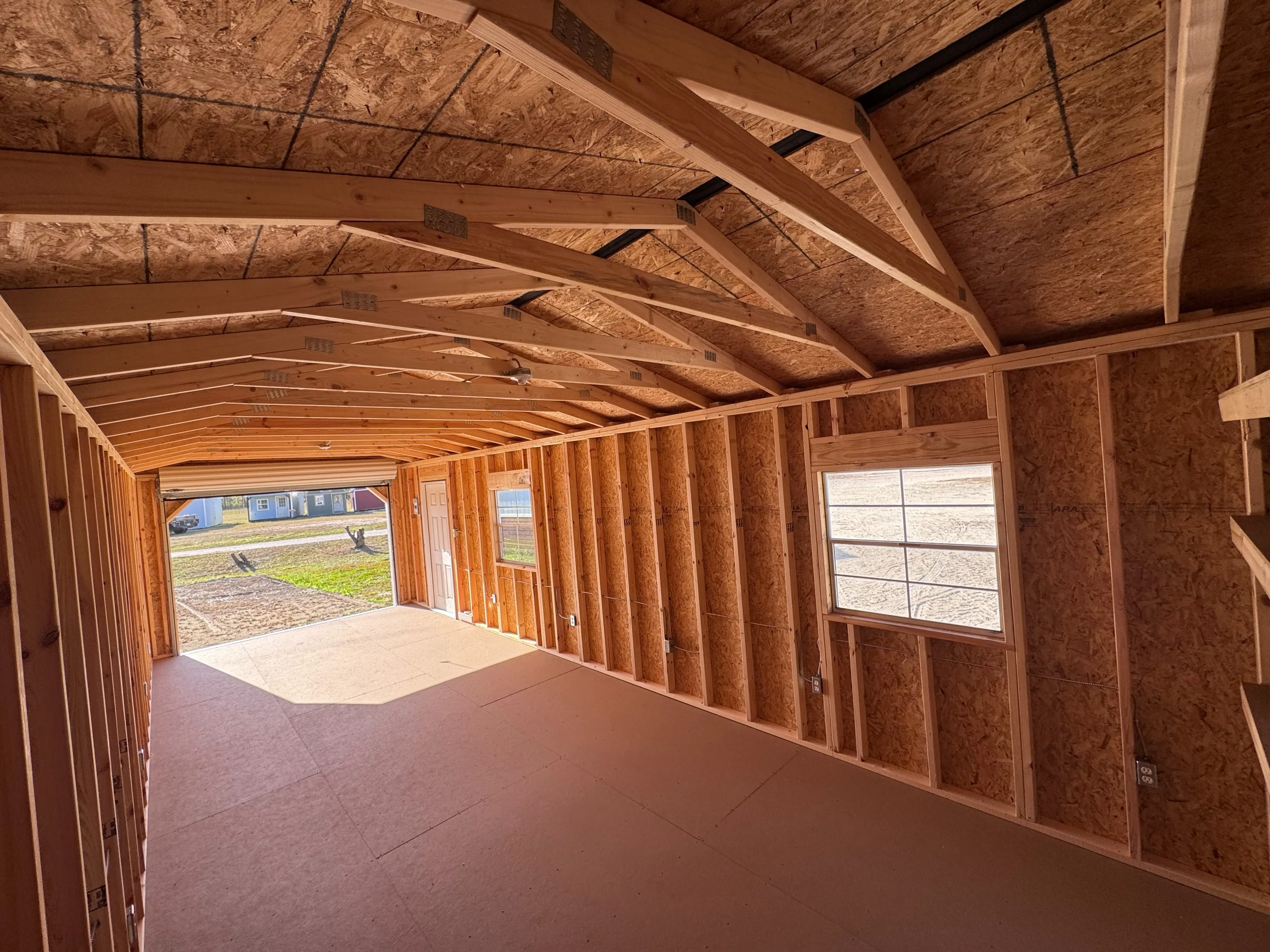 Interior view of 12x32 workshop showing roll up door opening, electrical outlets, and two non insulated windows