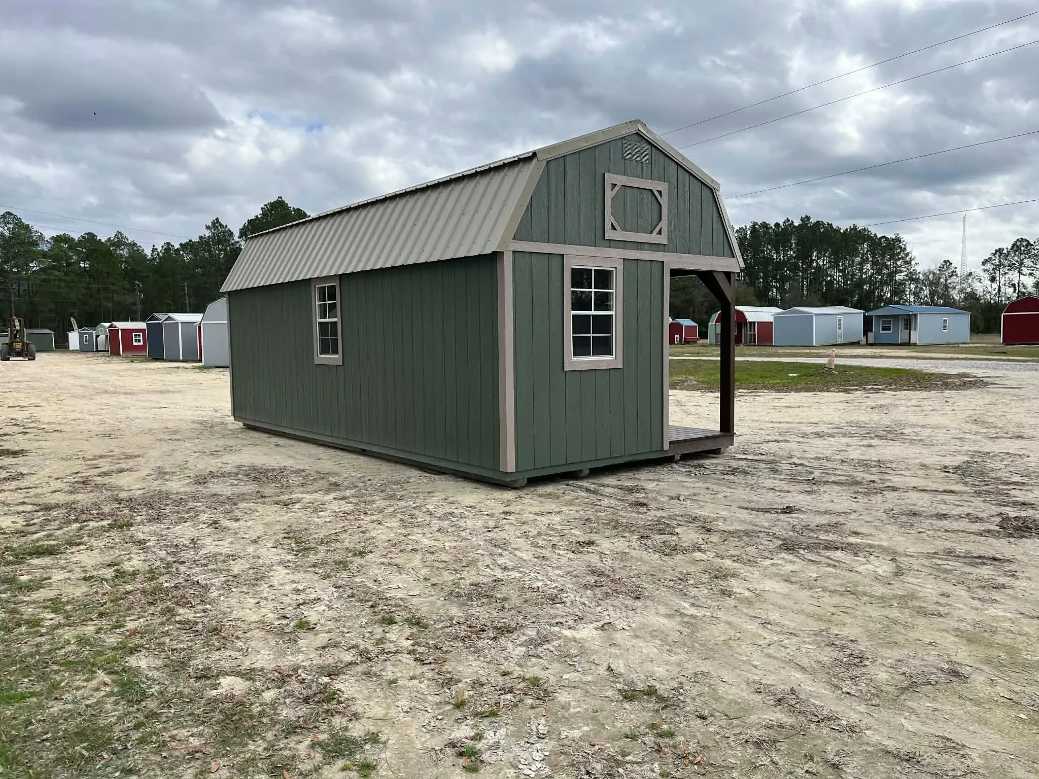 Exterior front side of a green 12x24 lofted corner porch cabin showing the windows