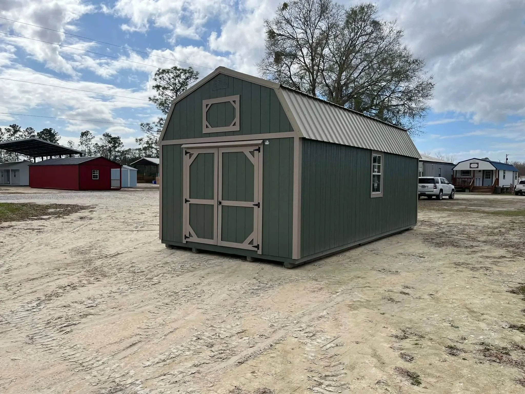 Exterior rear of a green 12x24 lofted corner porch cabin showing a double wood door and window