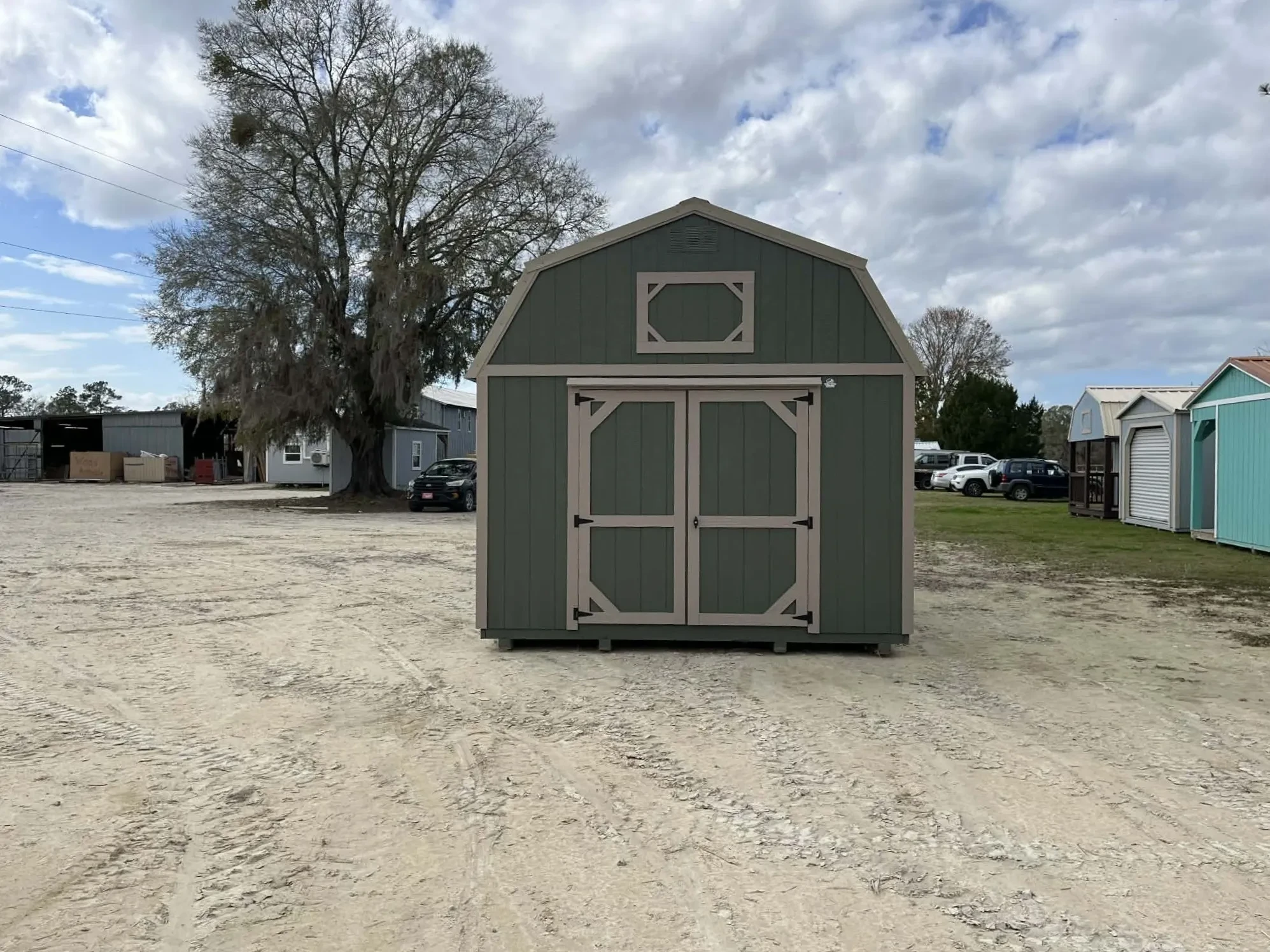 Exterior rear of a green 12x24 lofted corner porch cabin showing a double wood door