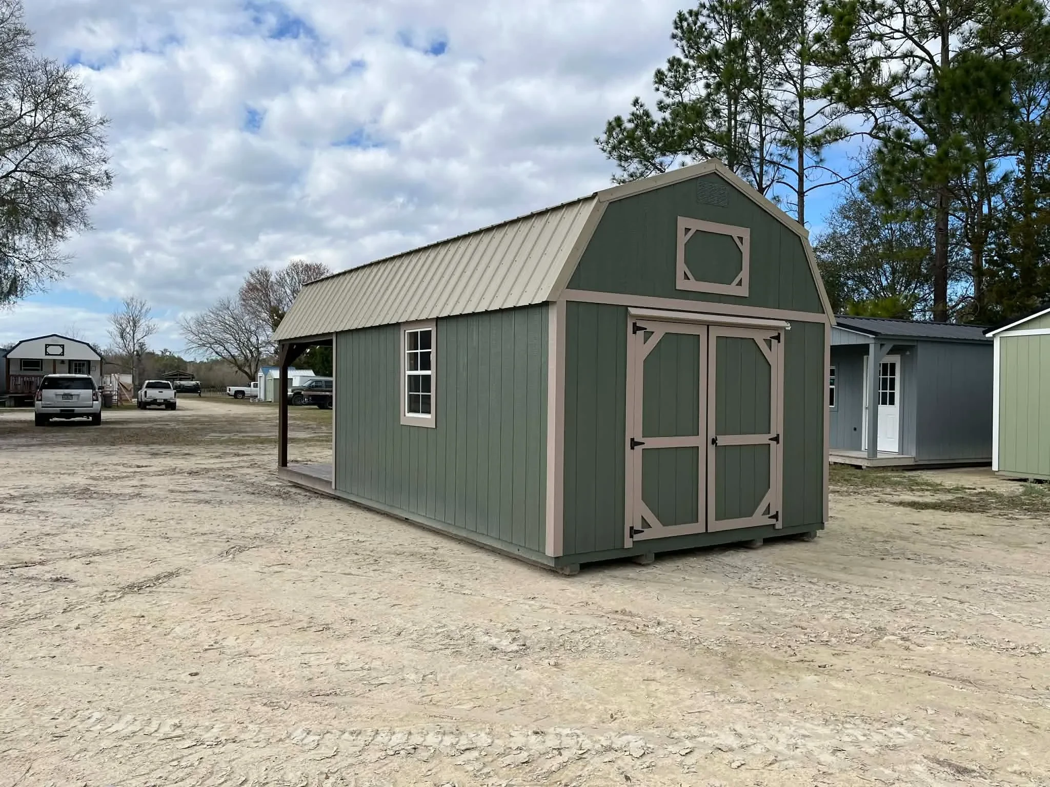 Exterior rear of a green 12x24 lofted corner porch cabin showing a double wood door and window