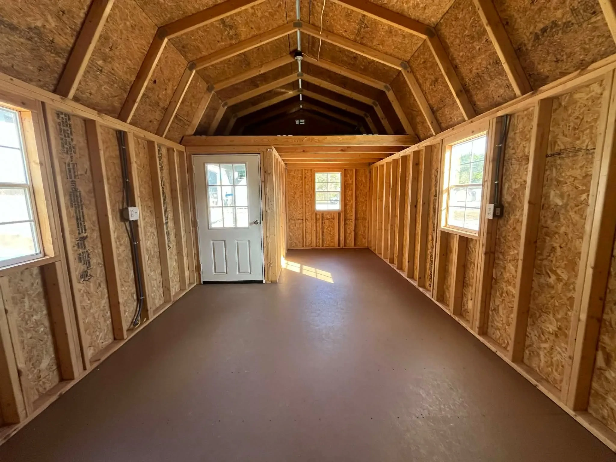 Interior of a 12x24 lofted corner porch cabin showing the loft, walk-n door and windows
