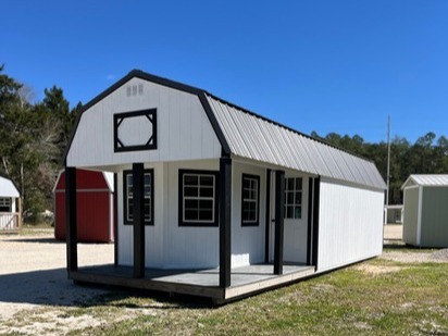 white and black deluze lofted cabin with a L-shaped porch, multiple windows, and a walk-in door with glass