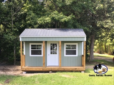 A gray side porch cabin with two windows and a 9-lite walk-in door on the porch