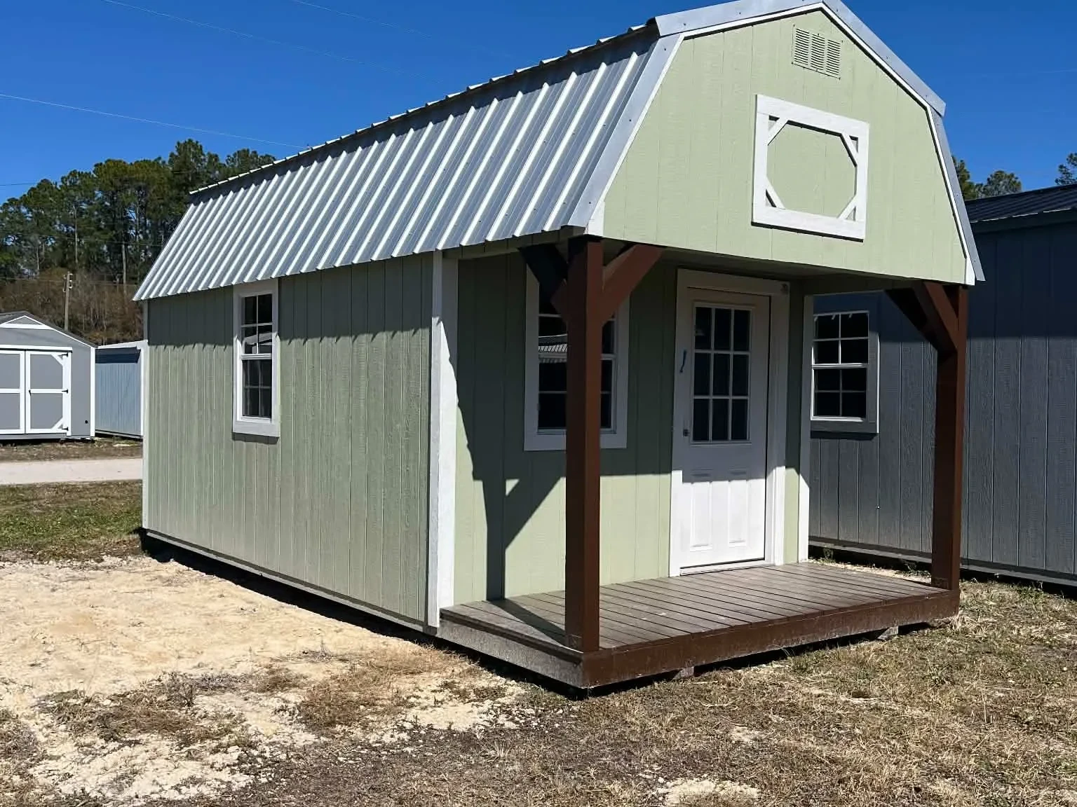 Exterior of a green 10x20 Lofted Barn Cabin showing a porch, walk-in Door and windows