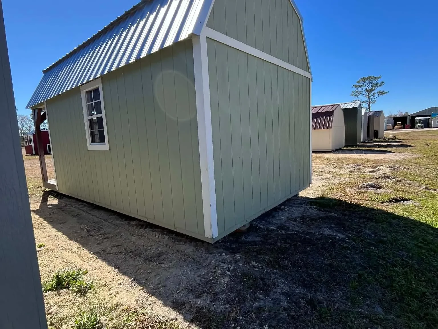 Exterior rear of a green 10x20 Lofted Barn Cabin showing a window