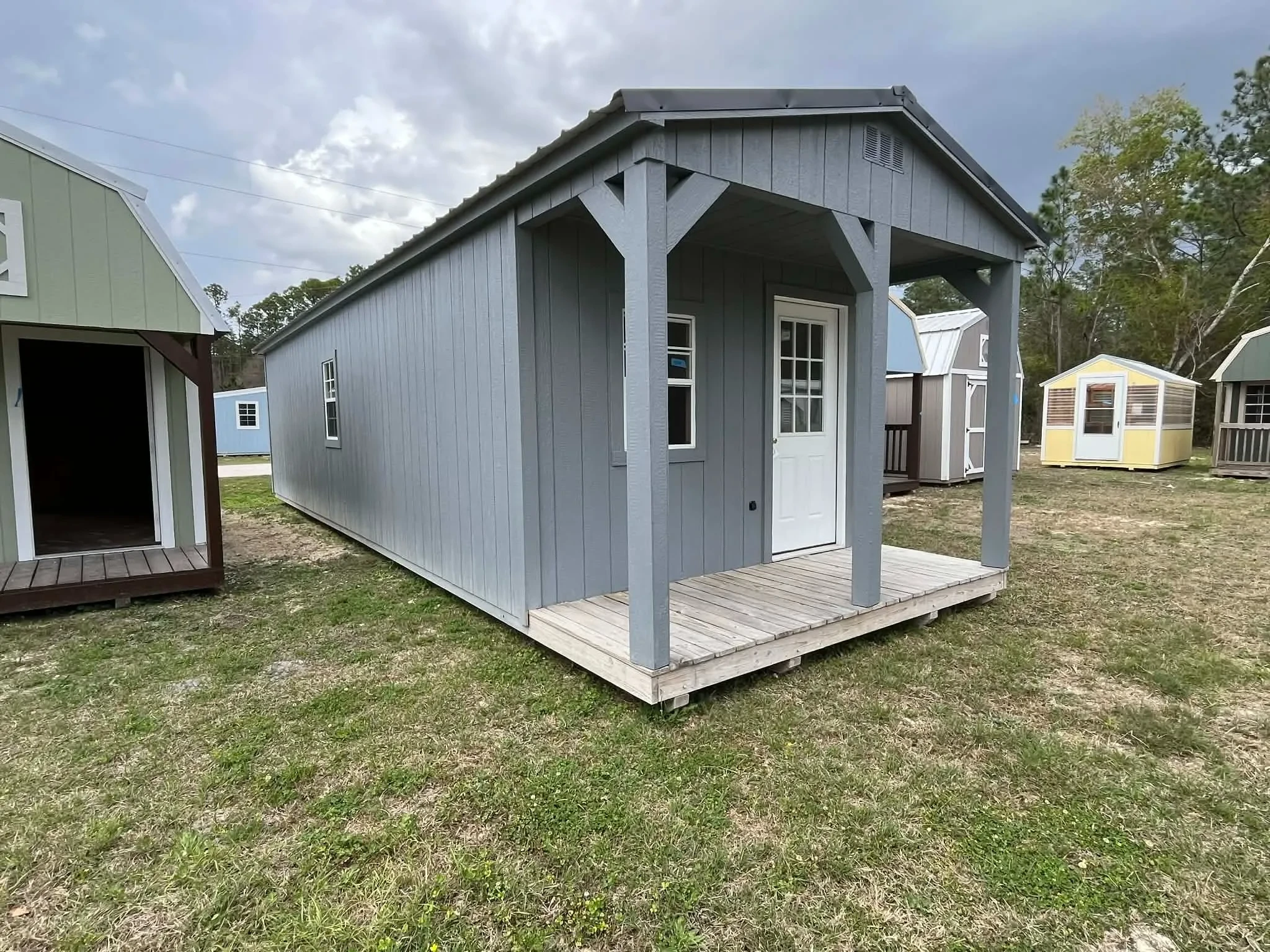 Exterior left front side of a dark grey 12x36 Cabin with a porch, entry door and windows