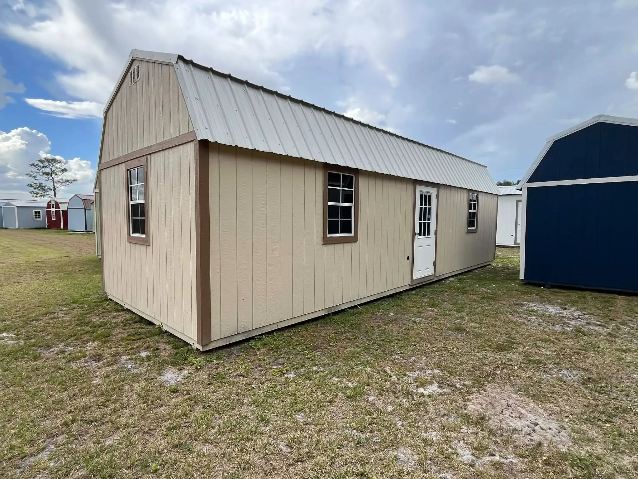 Exterior view of a 12x32 almond side lofted barn with an entry door and windows