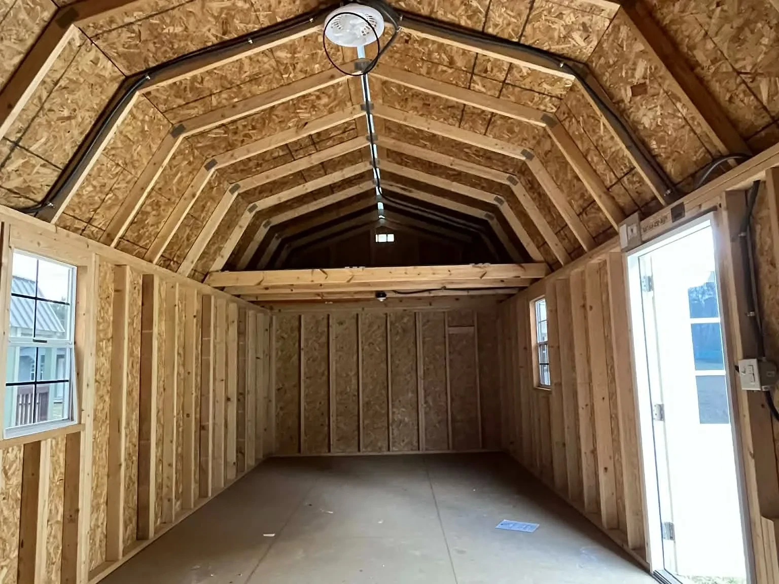 Interior view of a 12x32 side lofted barn showing the entry door, windows and loft