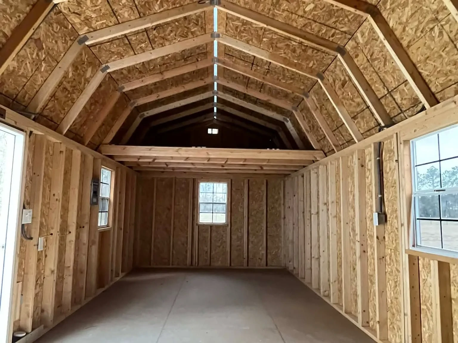 Interior view of a 12x32 side lofted barn showing the entry door, windows, electric and loft