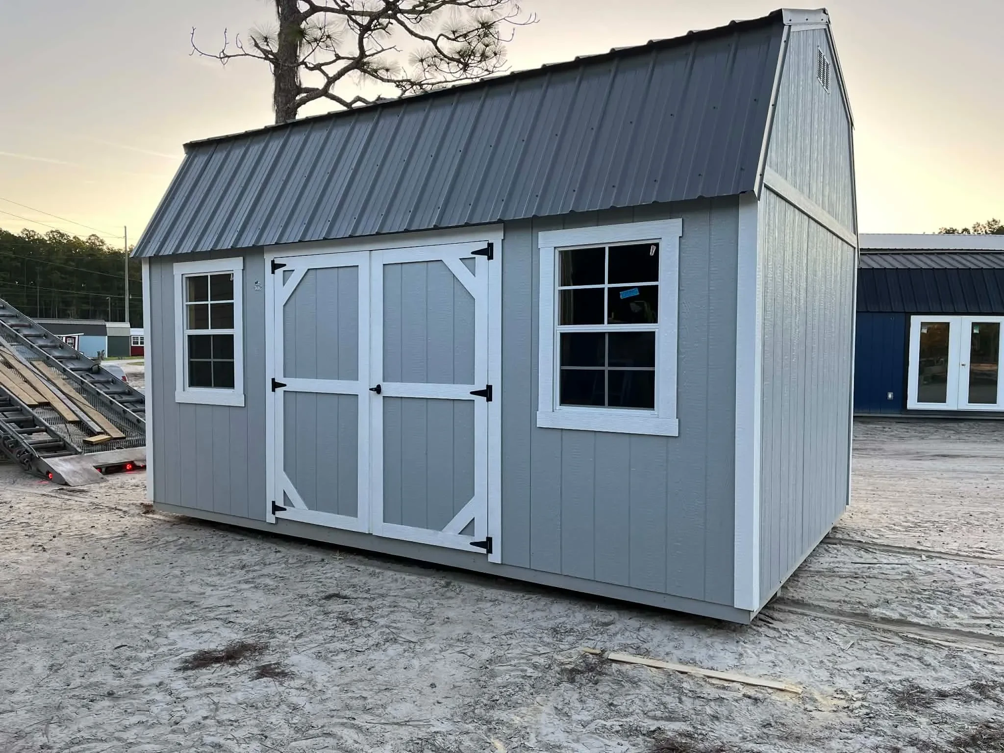 Exterior view of a grey 10x16 side lofted barn showing windows and door