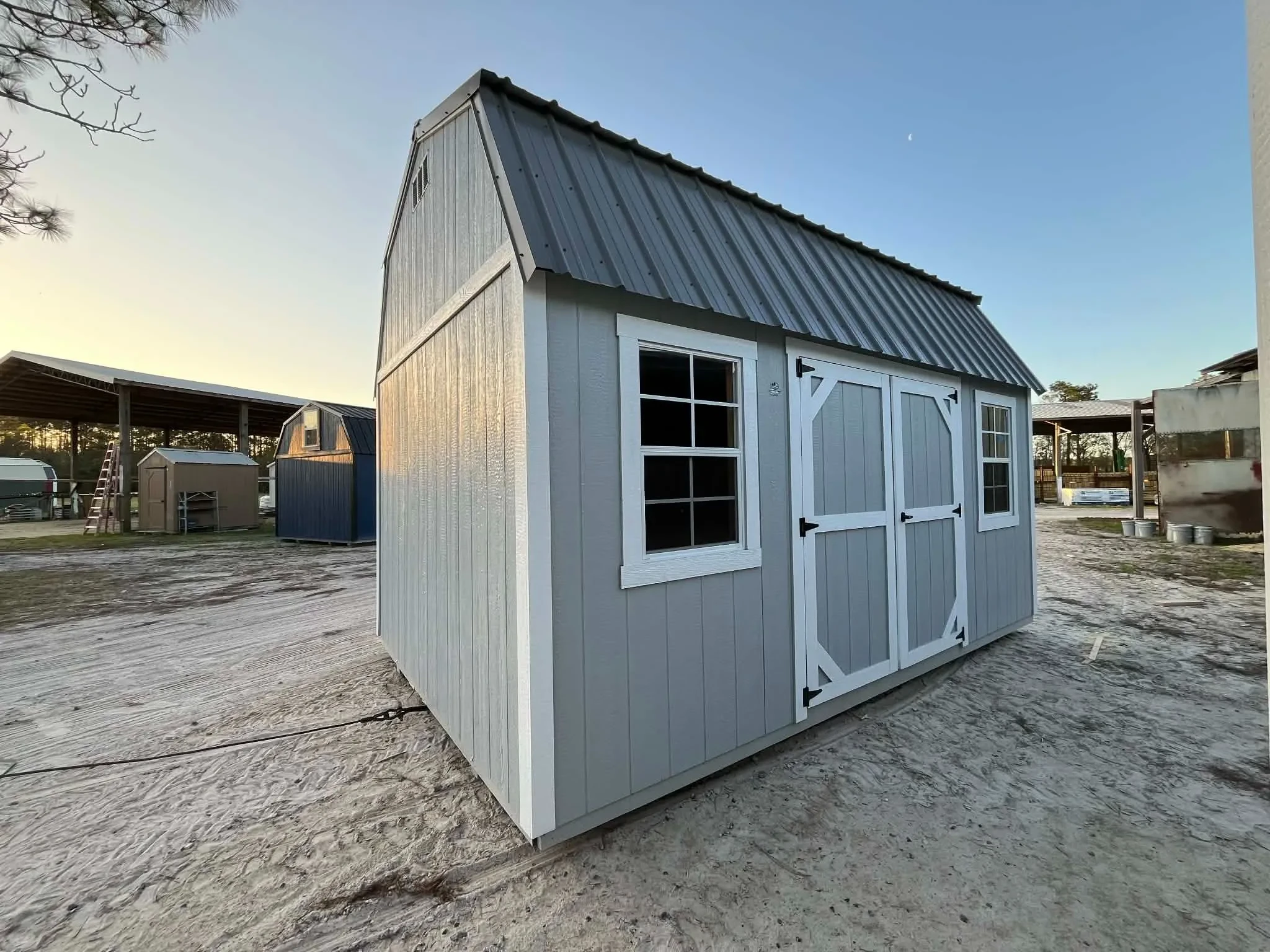 Exterior view of a grey 10x16 side lofted barn showing windows and door