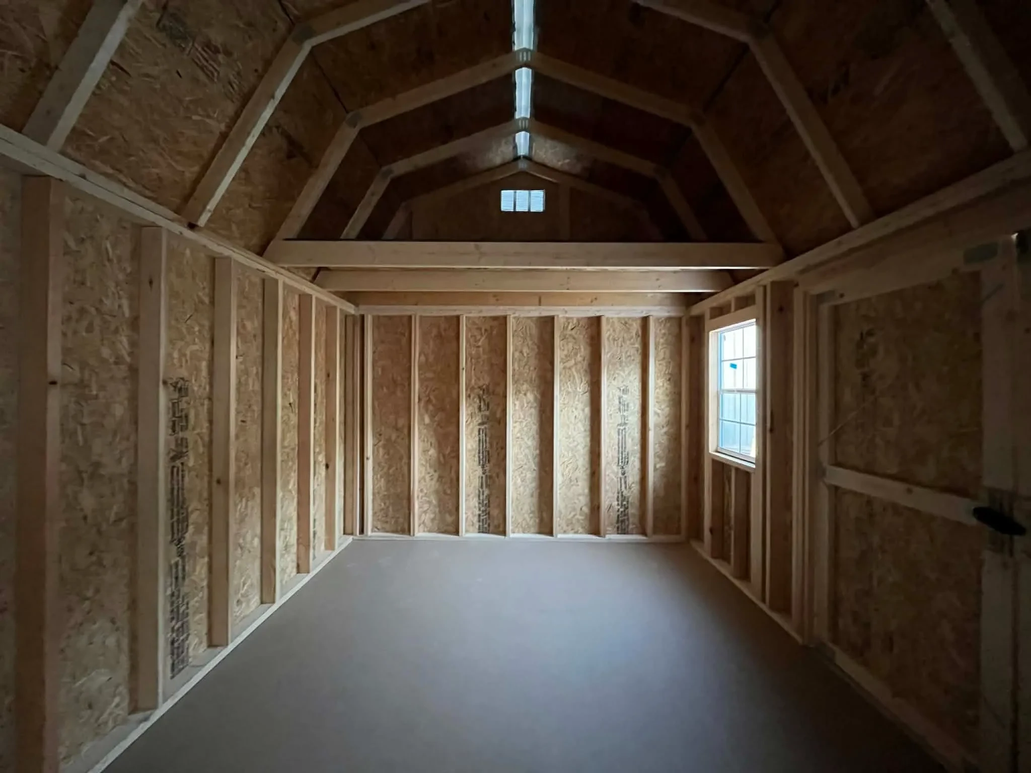 Interior view of a 10x16 side lofted barn showing the loft area, window and door
