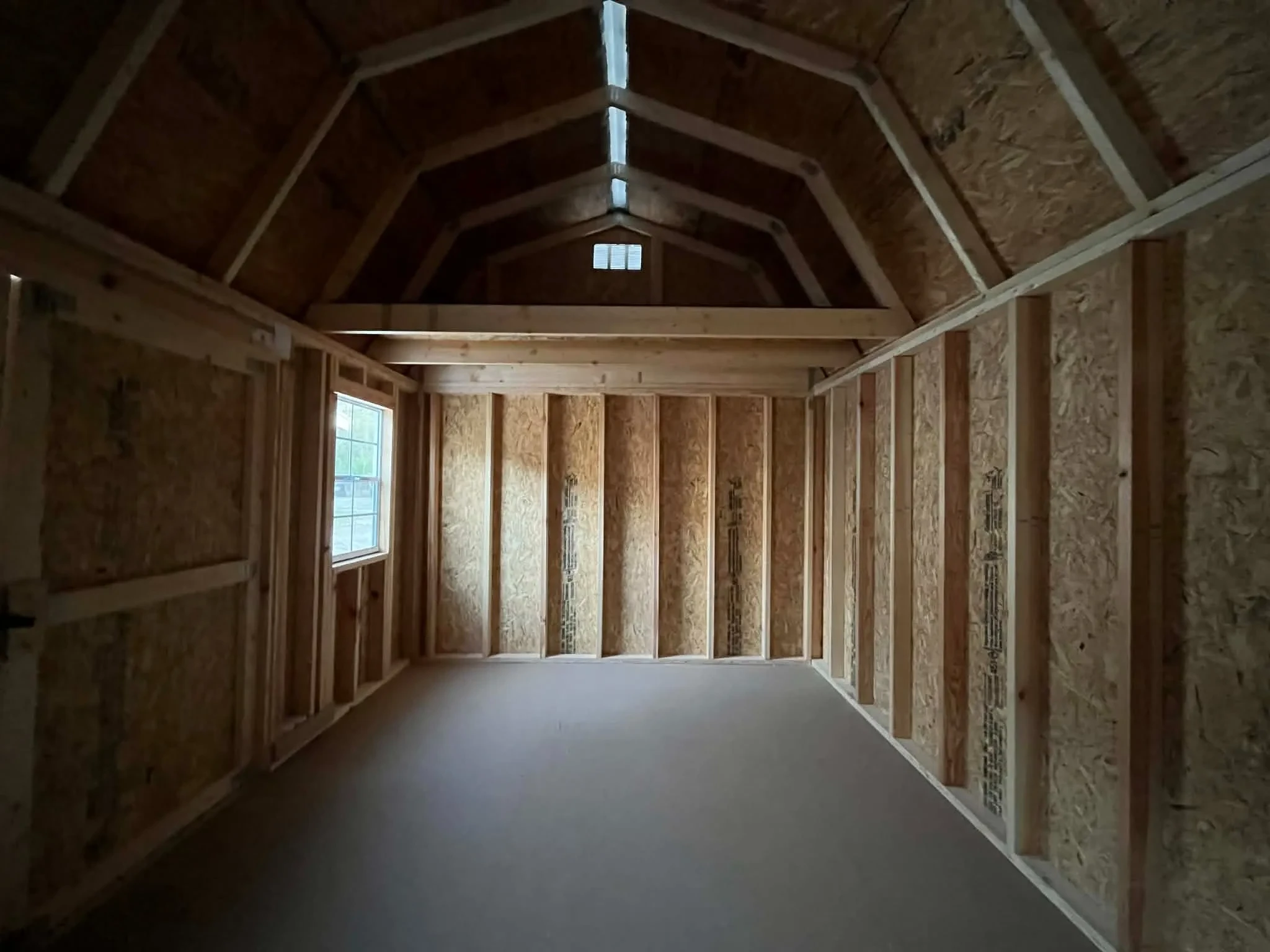 Interior view of a 10x16 side lofted barn showing the loft area, window and door