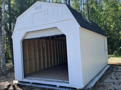 a white lofted barn workshop with an open garage door in the end