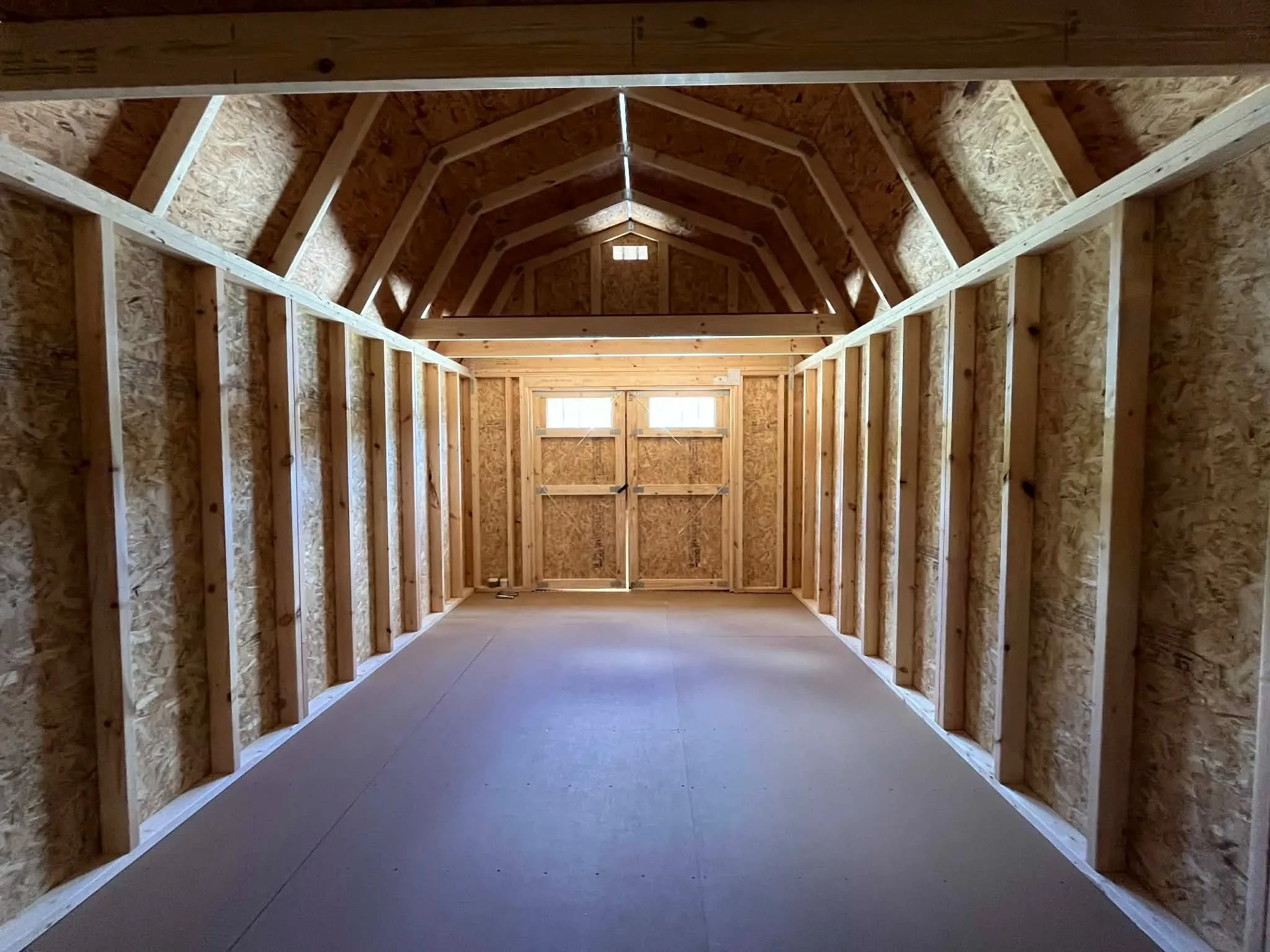 Interior of of a 10x20 lofted barn showing from back wall viewing the loft and doors