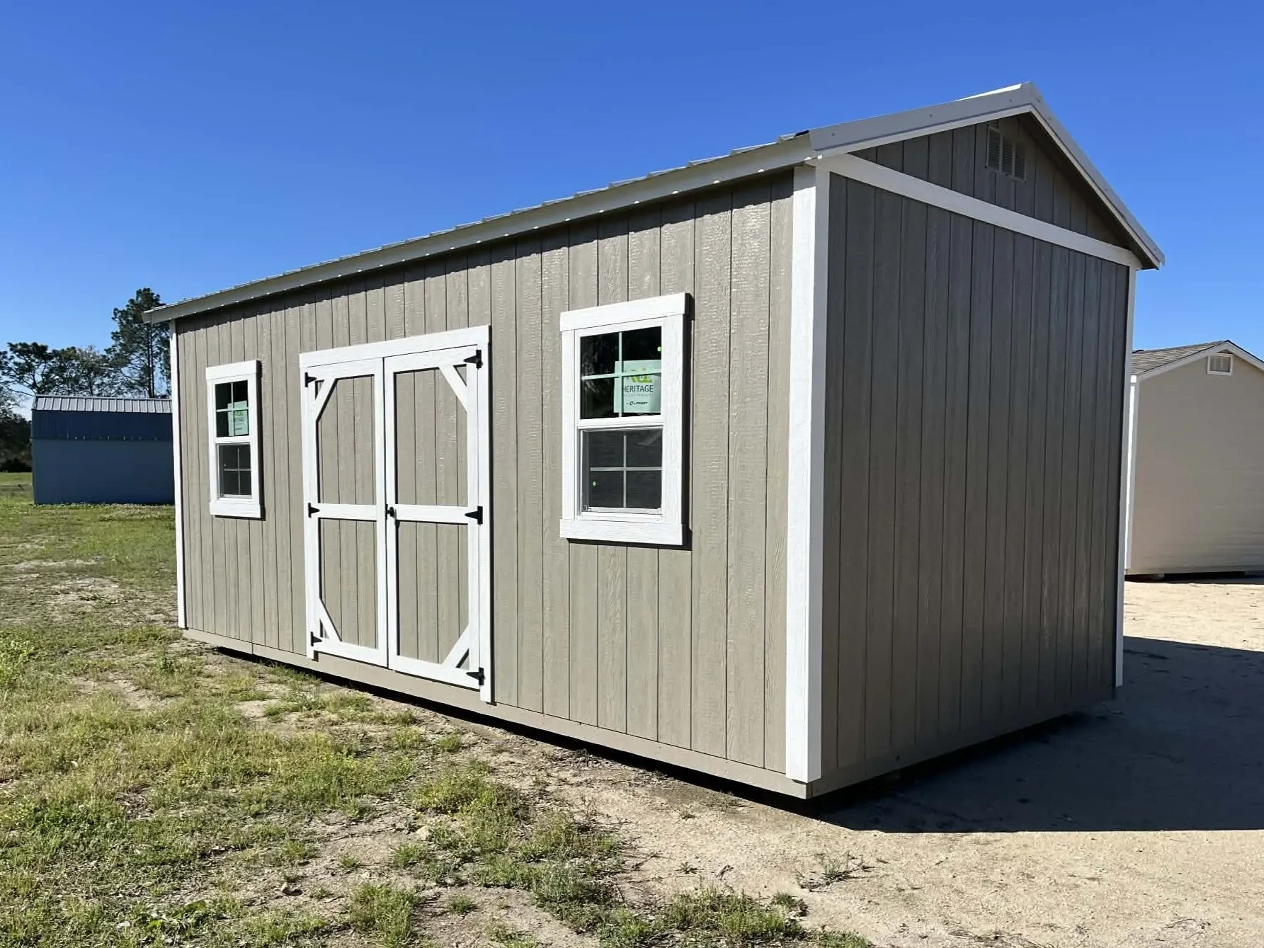 Exterior side view of a clay color 10x20 side garden shed showing the windows and door