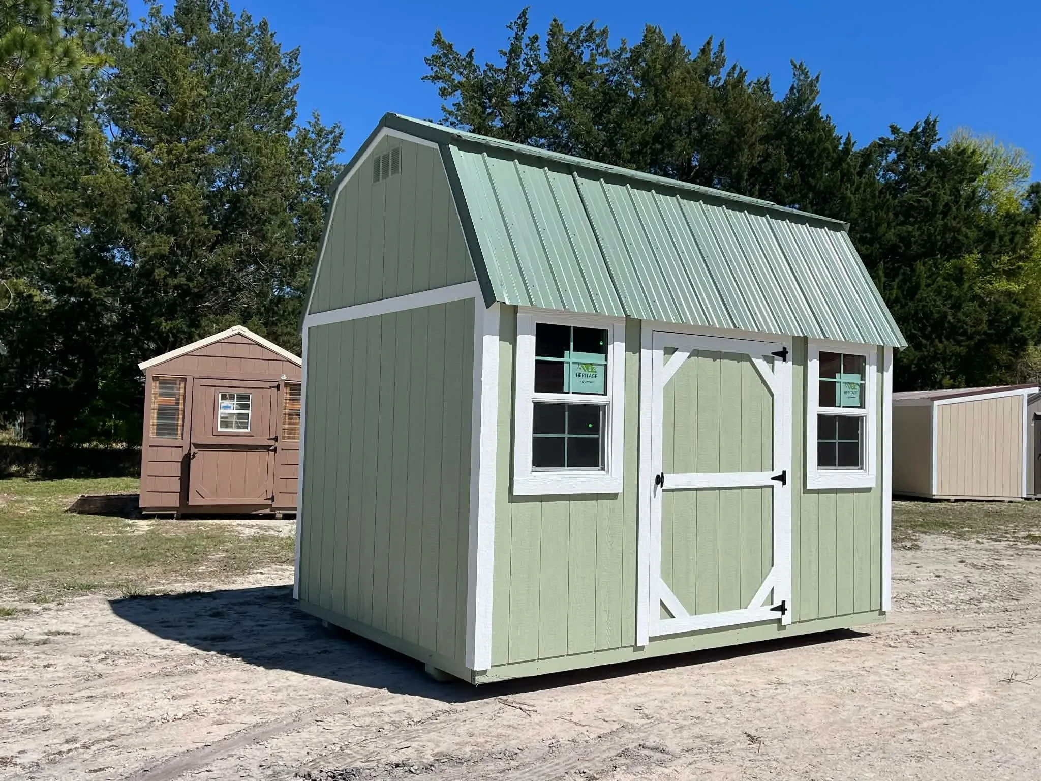 Exterior side view of a green 8x12 side lofted barn showing the door and windows