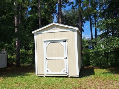 stone and white garden shed in a backyard in front of trees