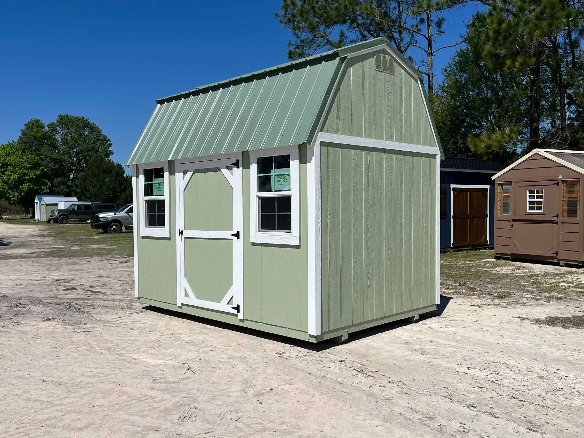 Exterior side view of a green 8x12 side lofted barn showing the door and windows