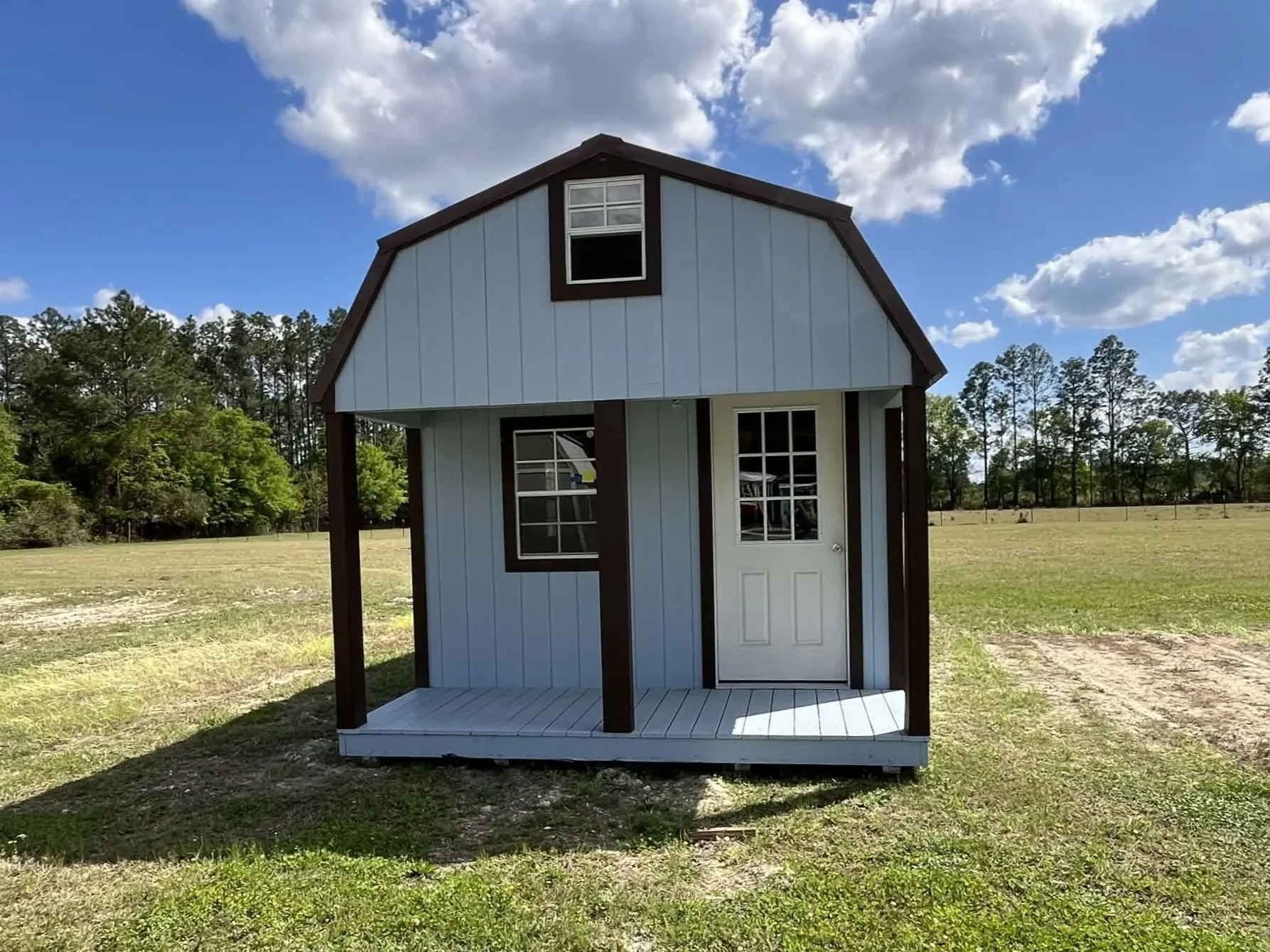 Exterior view of a light blue 12x28 lofted barn cabin showing the porch, walk-in door and windows