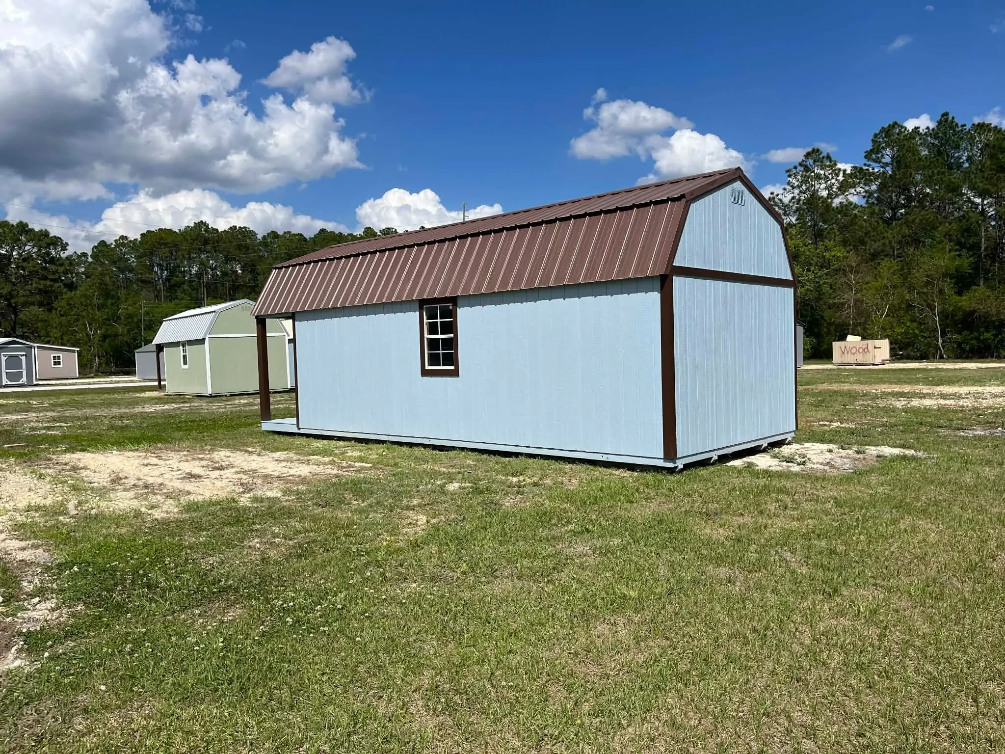 Exterior rear side view of a light blue 12x28 lofted barn cabin showing a window