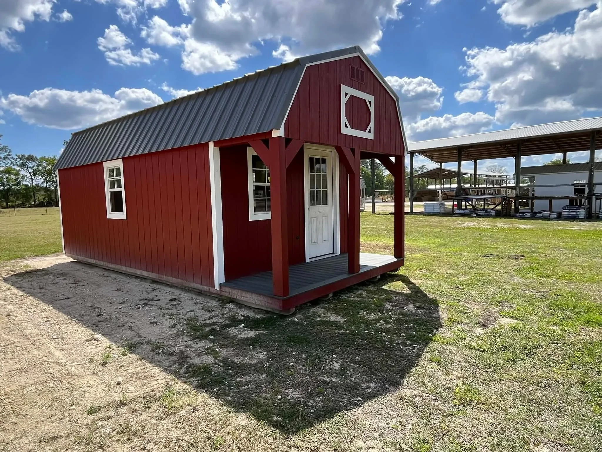 Exterior front side view of a 12x24 lofted barn cabin showing the porch, walk-in door and windows