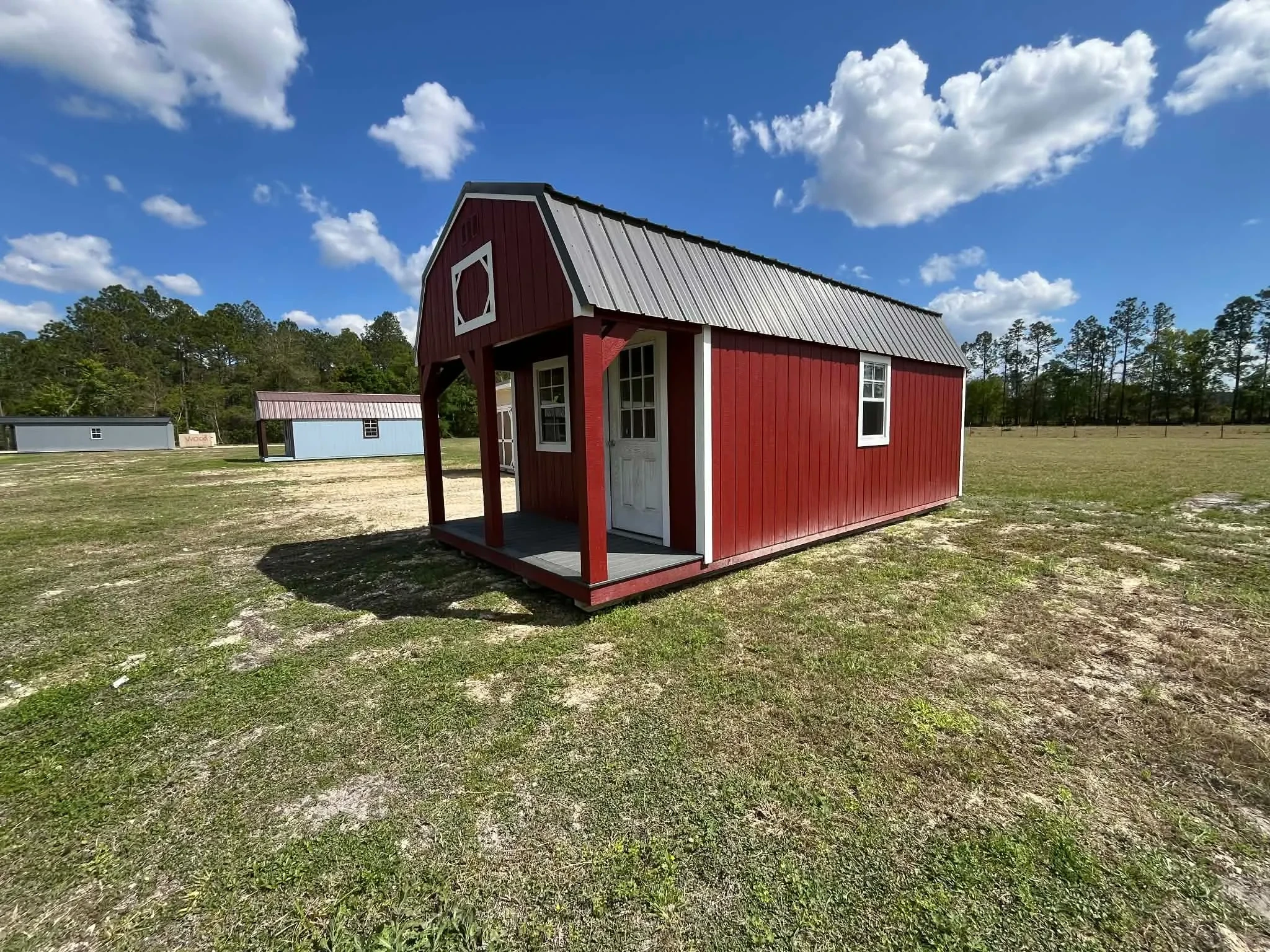 Exterior front side view of a 12x24 lofted barn cabin showing the porch, walk-in door and windows