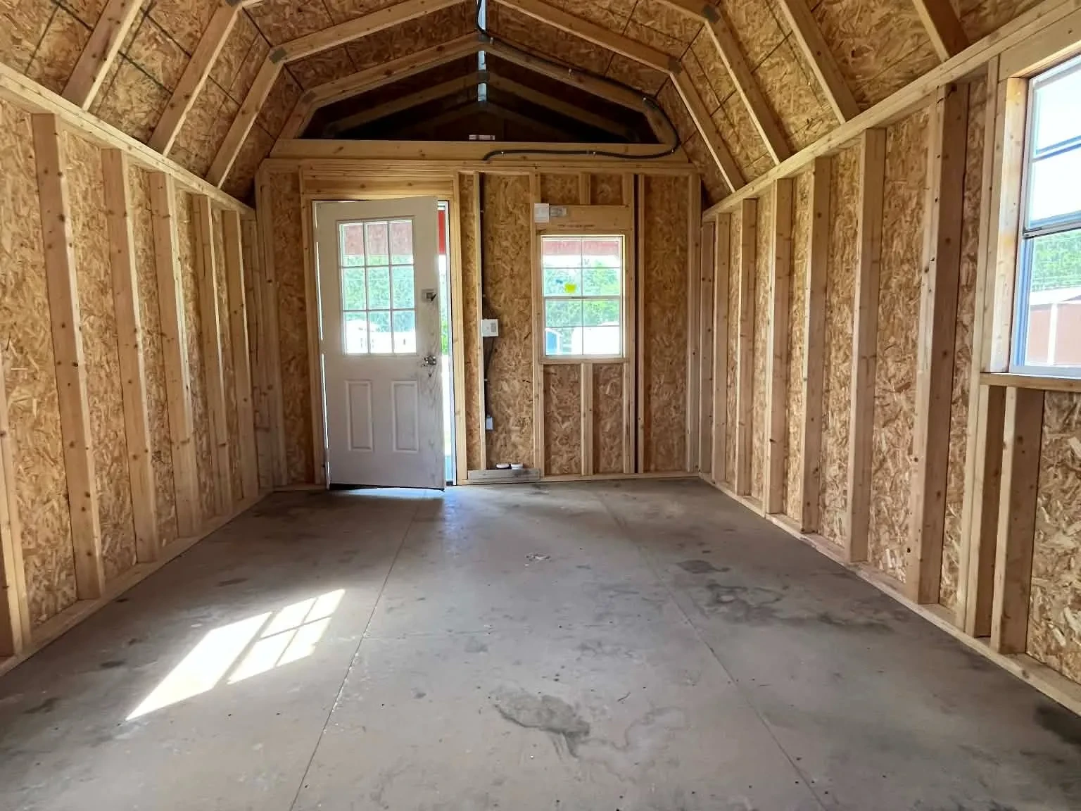 Interior view of a 12x28 lofted barn cabin showing the loft, walk-in door and window