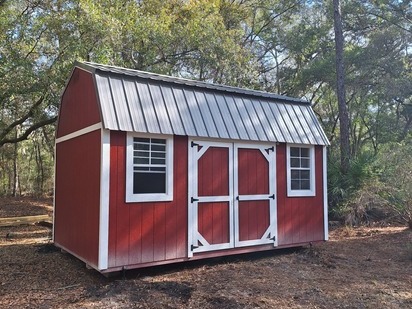 red and white lofted barn with double doors and two windows in the side