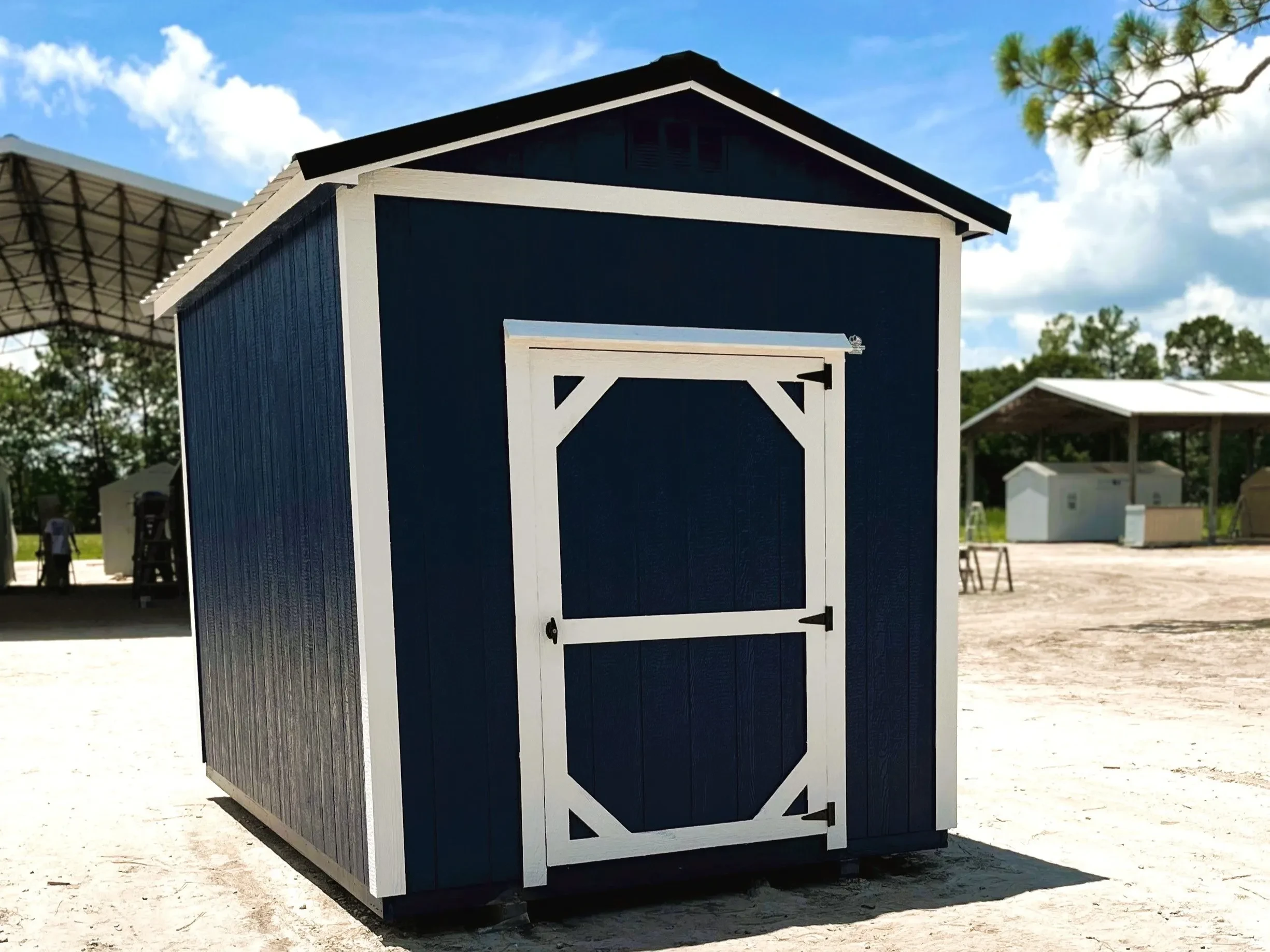 Outside of an 8x12 garden shed, painted dark blue with white trim and a black metal roof