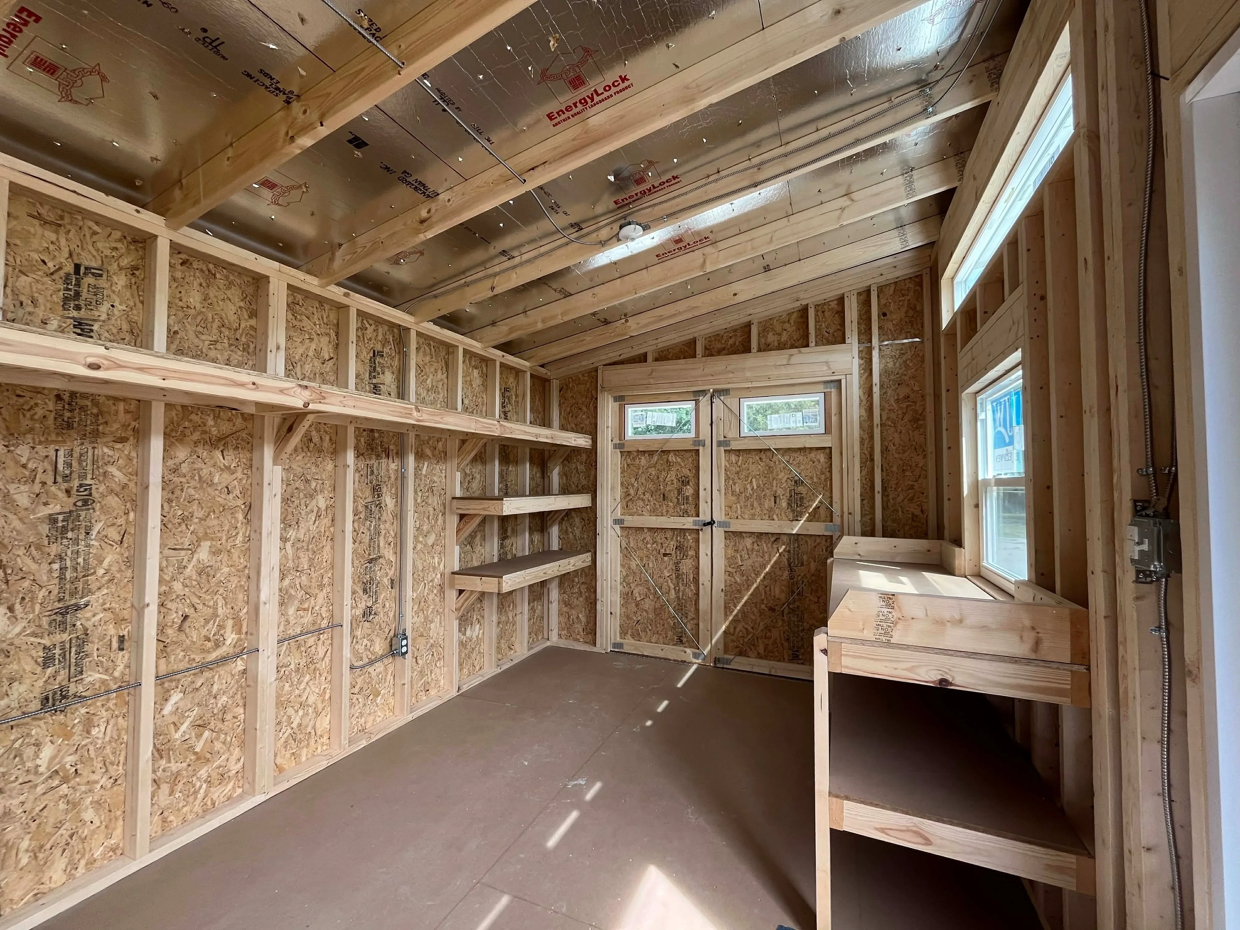 Interior view of a 10x24 urban showing wood doors, shelving and workbench
