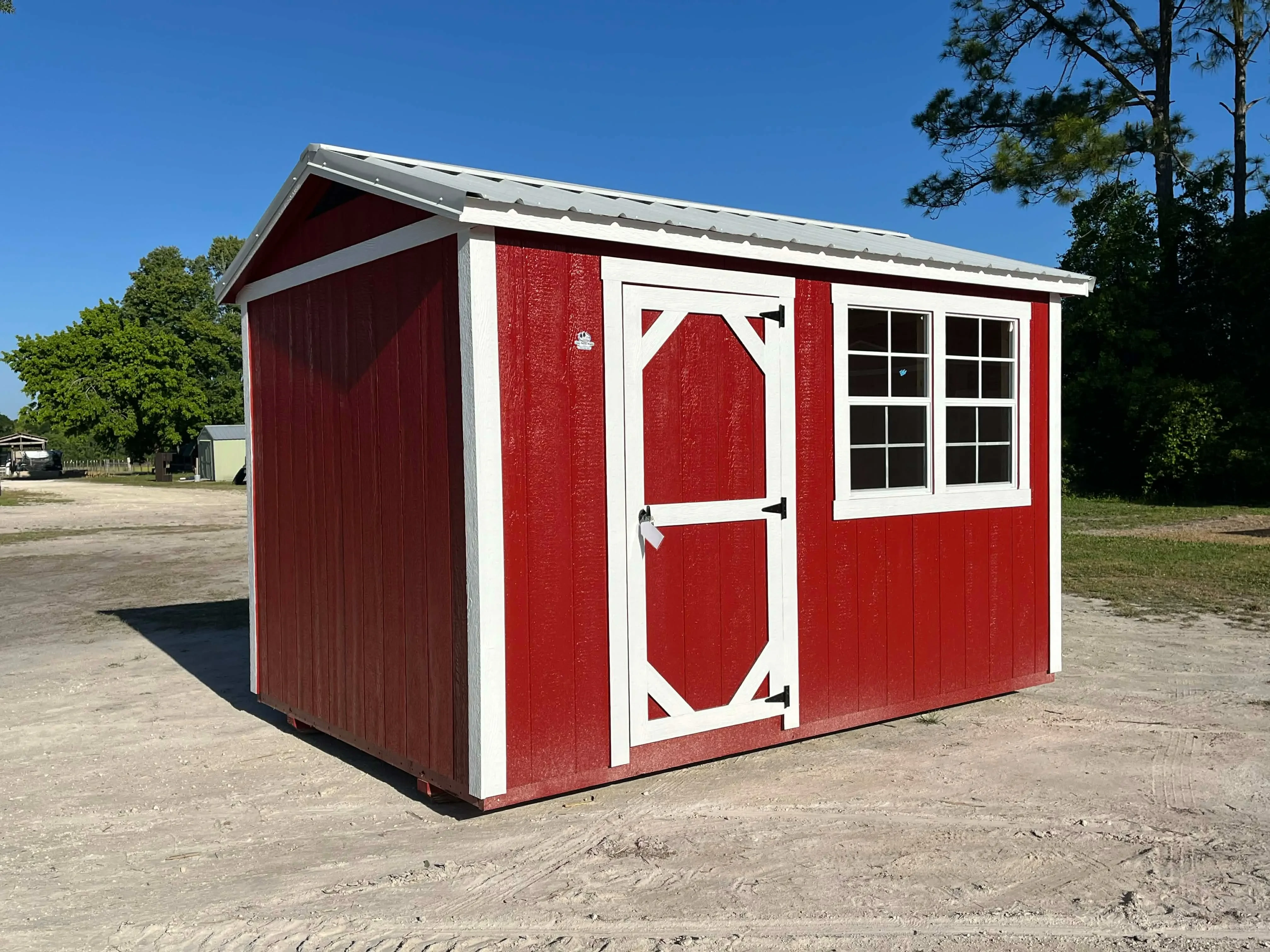 Exterior front view of a red 8x12 chicken coop with a wood door and windows