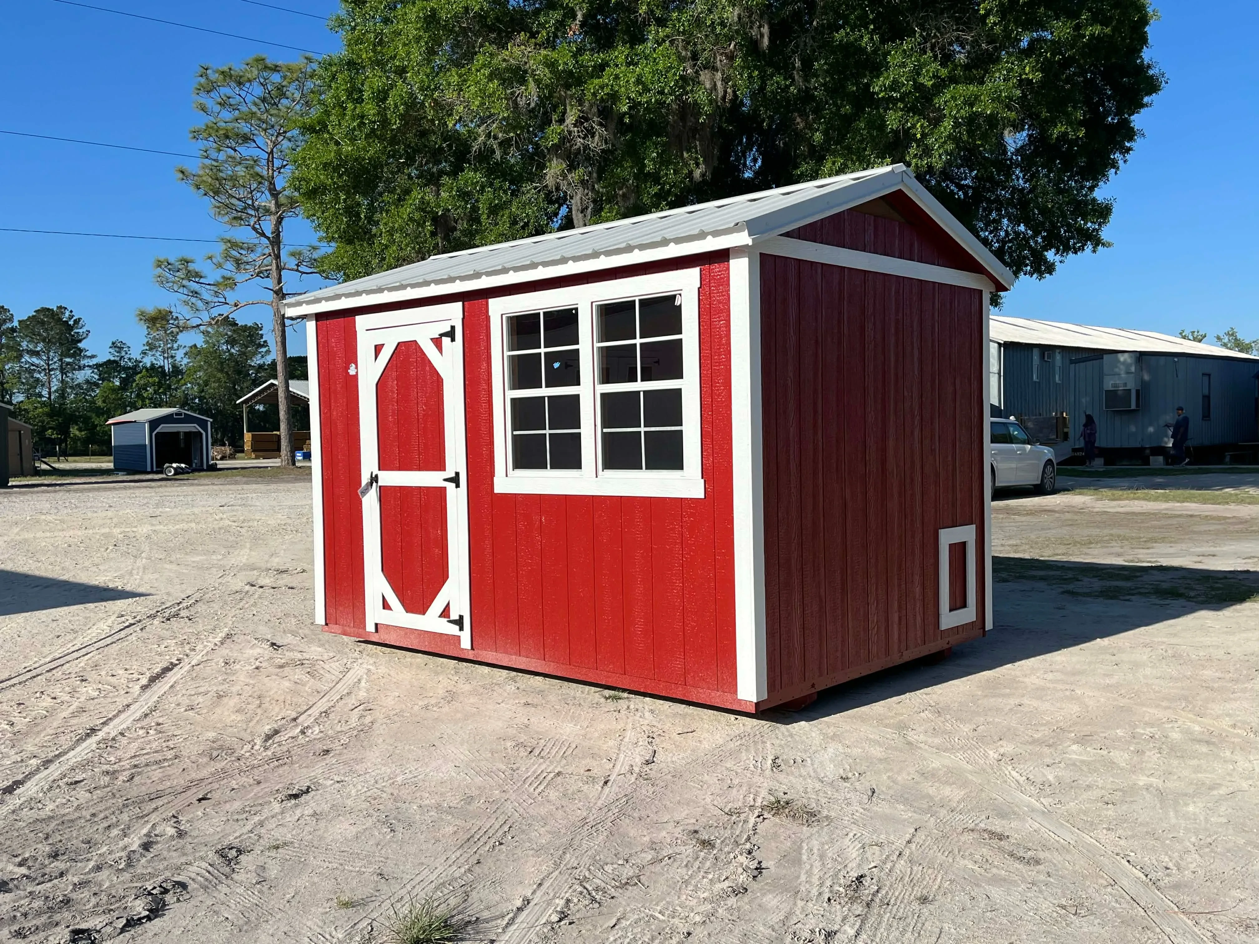 Exterior front view of a red 8x12 chicken coop with a wood door and windows