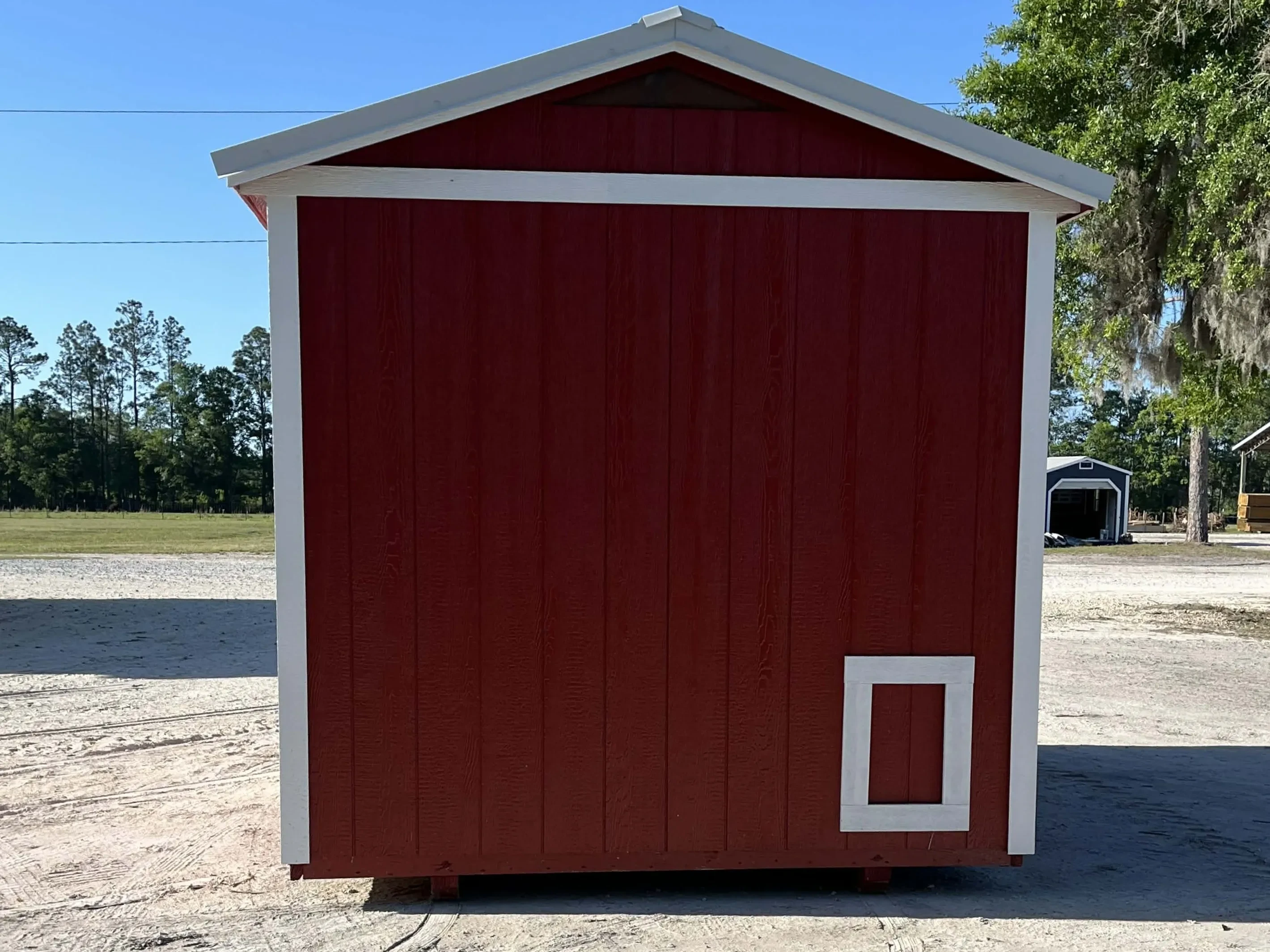 Exterior side view of a red 8x12 chicken coop with a chicken run door