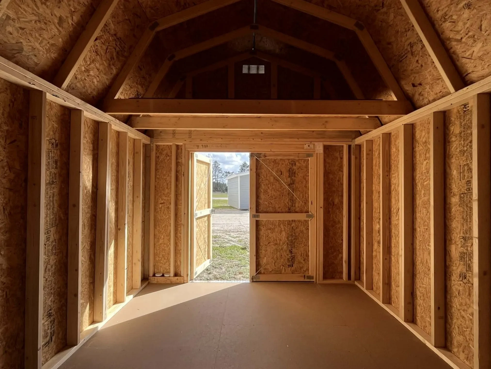 Interior view of a 10x16 lofted barn showing the double wood doors and loft