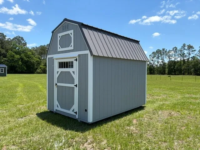 Exterior front right view of a grey 8x12 lofted barn showing the door with transom window.