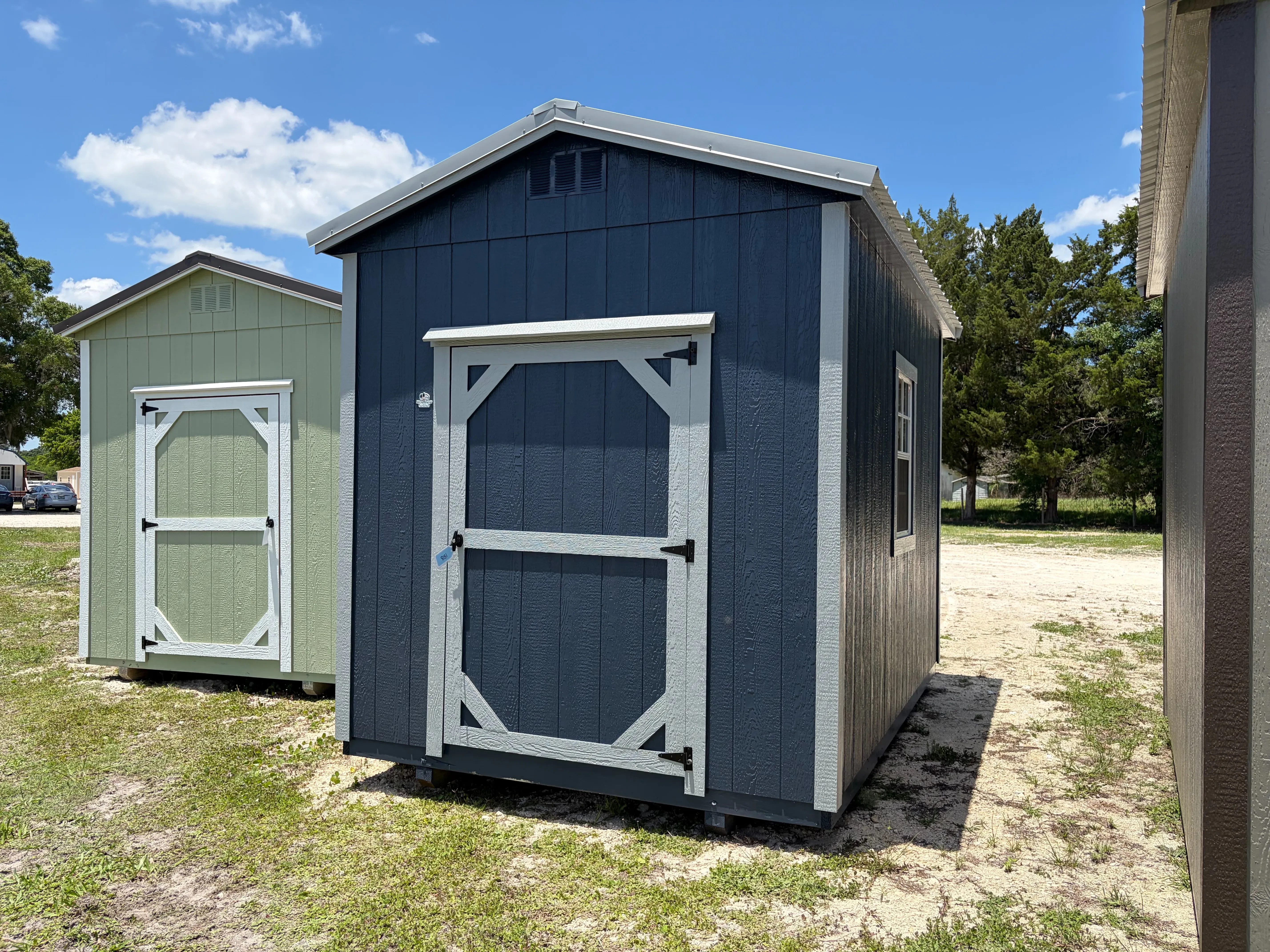 Exterior front view of dark blue 8x12 garden shed with a wood door